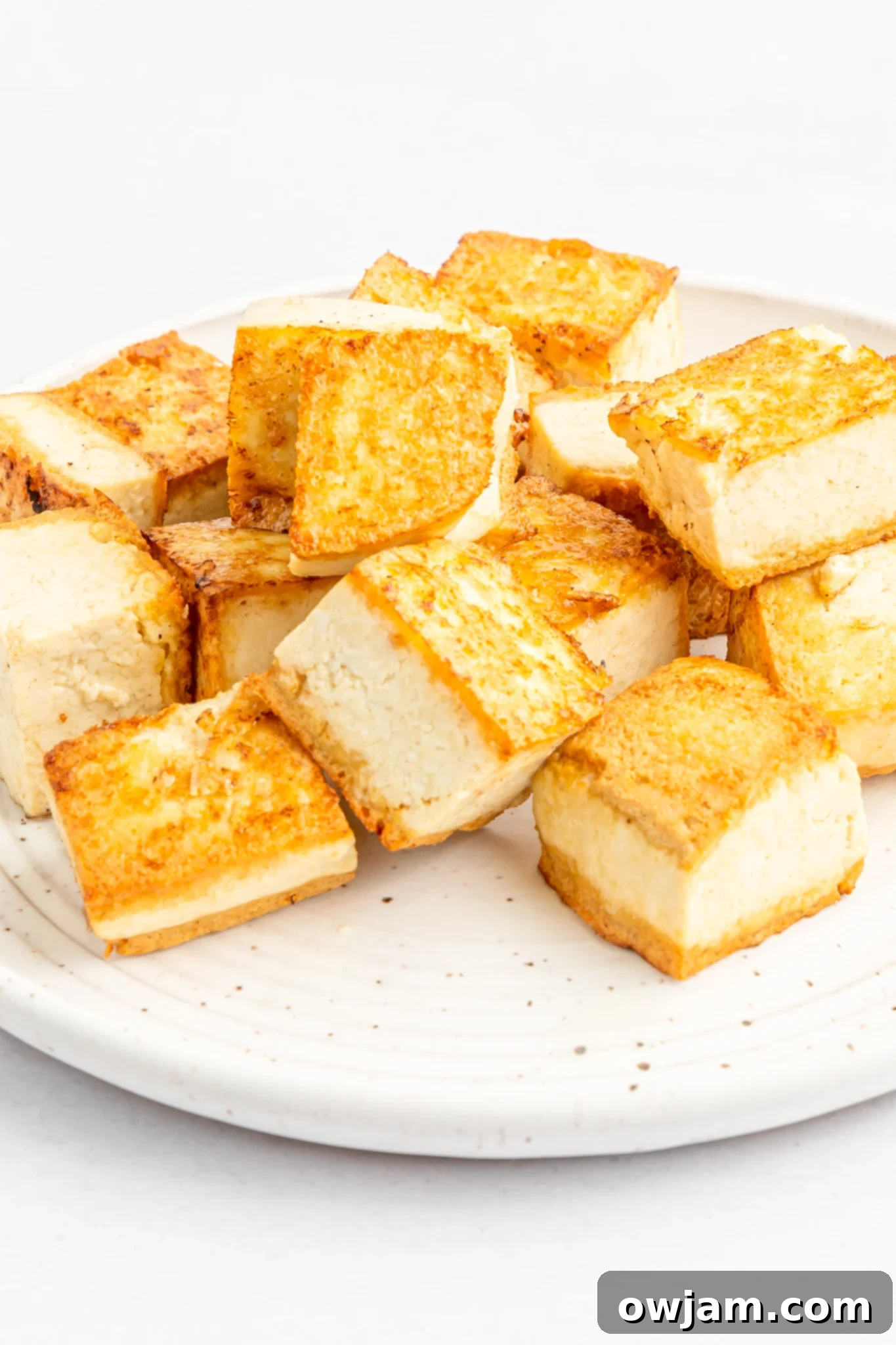 Crispy golden-brown tofu cubes arranged on a plate, ready to be added to the Thai Vegetable Green Curry.
