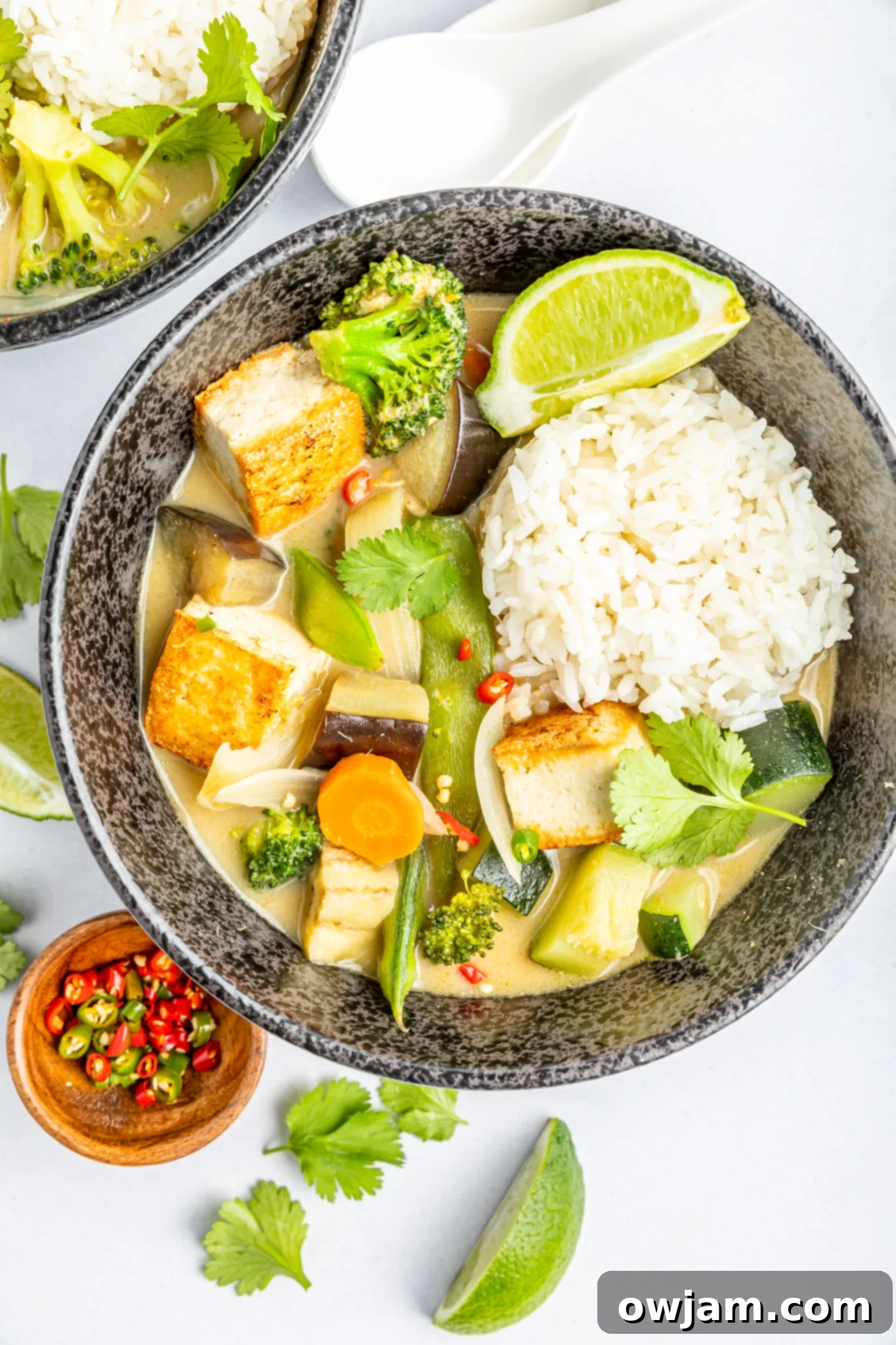 Thai Vegetable Green Curry in a bowl with fresh lime wedges on the side, ready for serving.