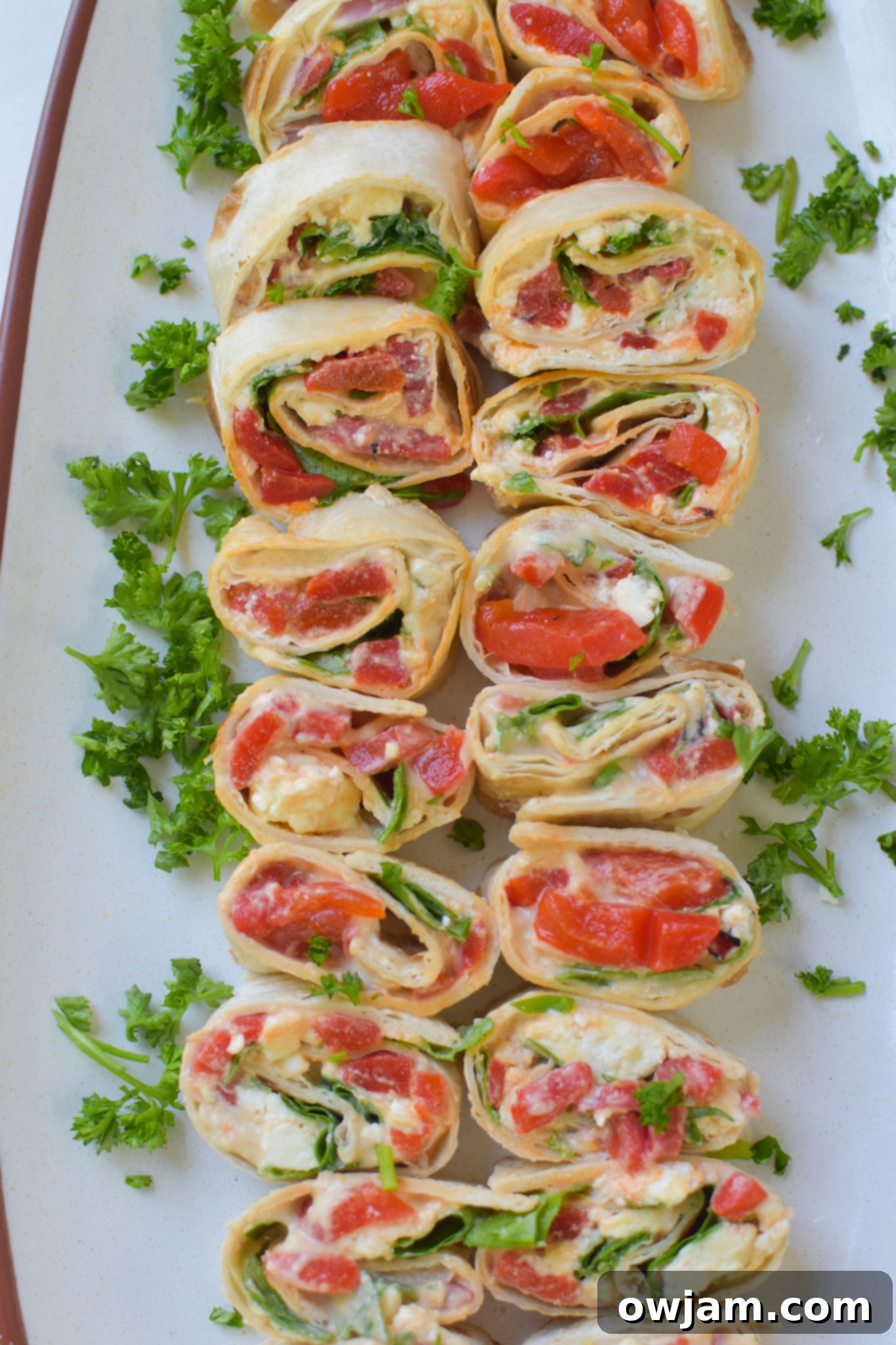 Savory Mediterranean Spirals 4 Mediterranean Pinwheels on a platter, garnished with fresh chopped parsley.