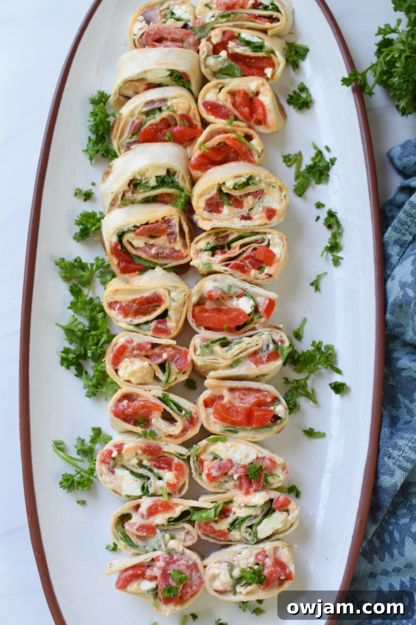 Savory Mediterranean Spirals 8 Fresh Mediterranean Pinwheels presented on a white plate alongside a blue linen napkin.