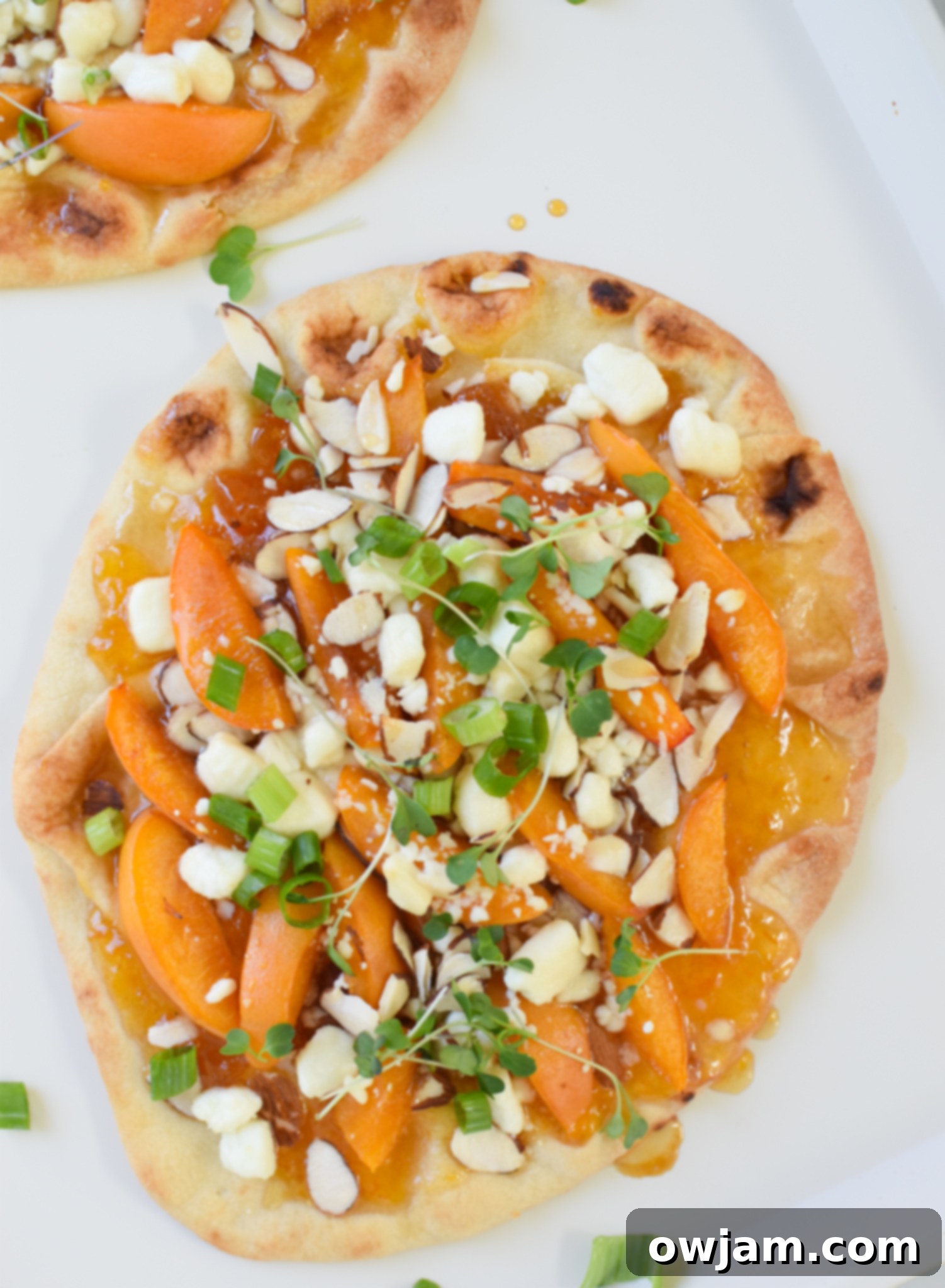 Goat Cheese Apricot Pizza on a white plate, close up shot with a fork cutting into a slice.