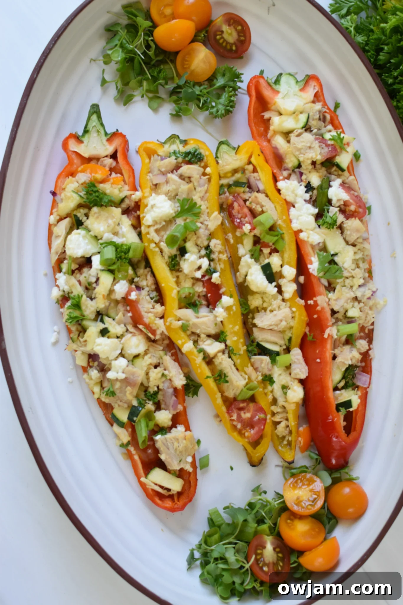 Flavorful Mediterranean Tuna Couscous Stuffed Bell Peppers 2 Mediterranean Tuna Couscous Stuffed Peppers on a white platter, showcasing the golden-grilled peppers filled with vibrant couscous and tuna mixture.