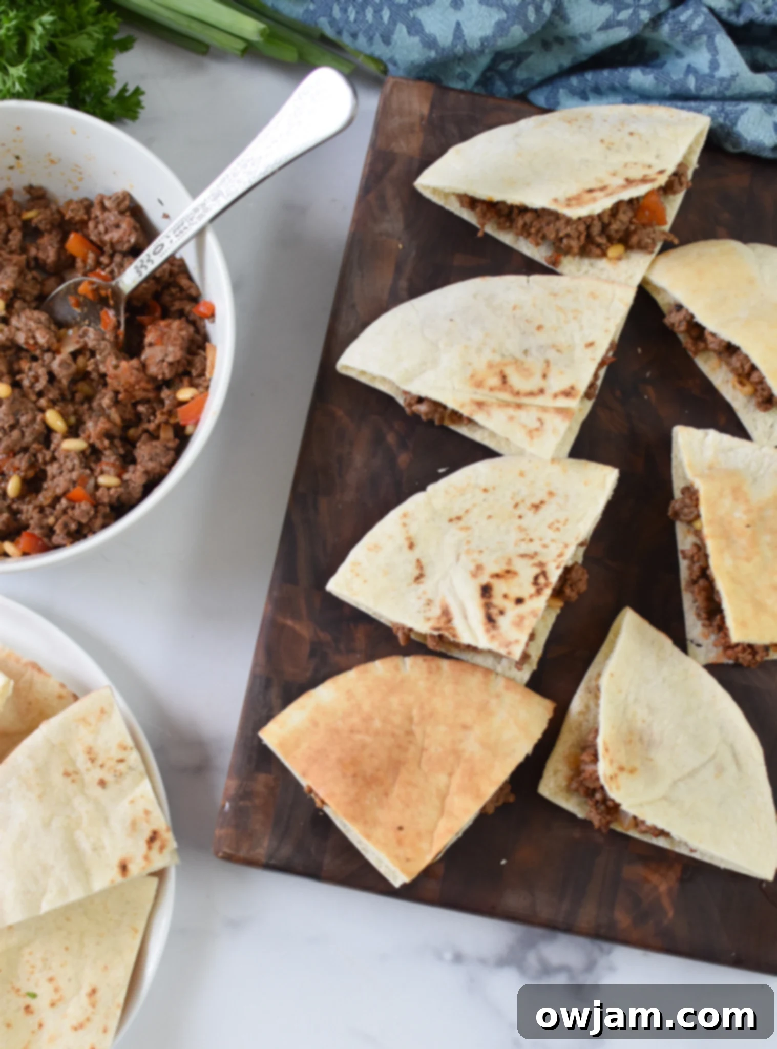 Arayes Lebanese Grilled Meat Stuffed Pitas 6 A tray of freshly prepared Lebanese Meat Stuffed Pitas, with one pita cut open to show the rich beef filling. They are golden-brown and ready to be served.