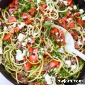 Mediterranean Ground Beef Zucchini Skillet in a skillet with a white spoon