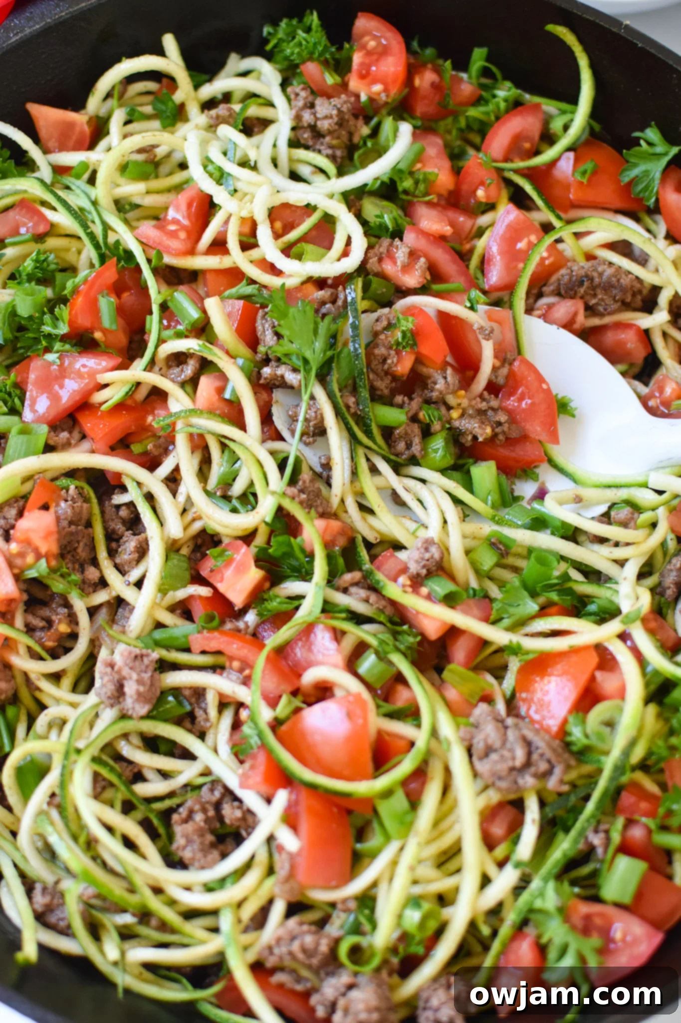 Mediterranean Ground Beef Zucchini Skillet with a serving spoon, showcasing its texture.