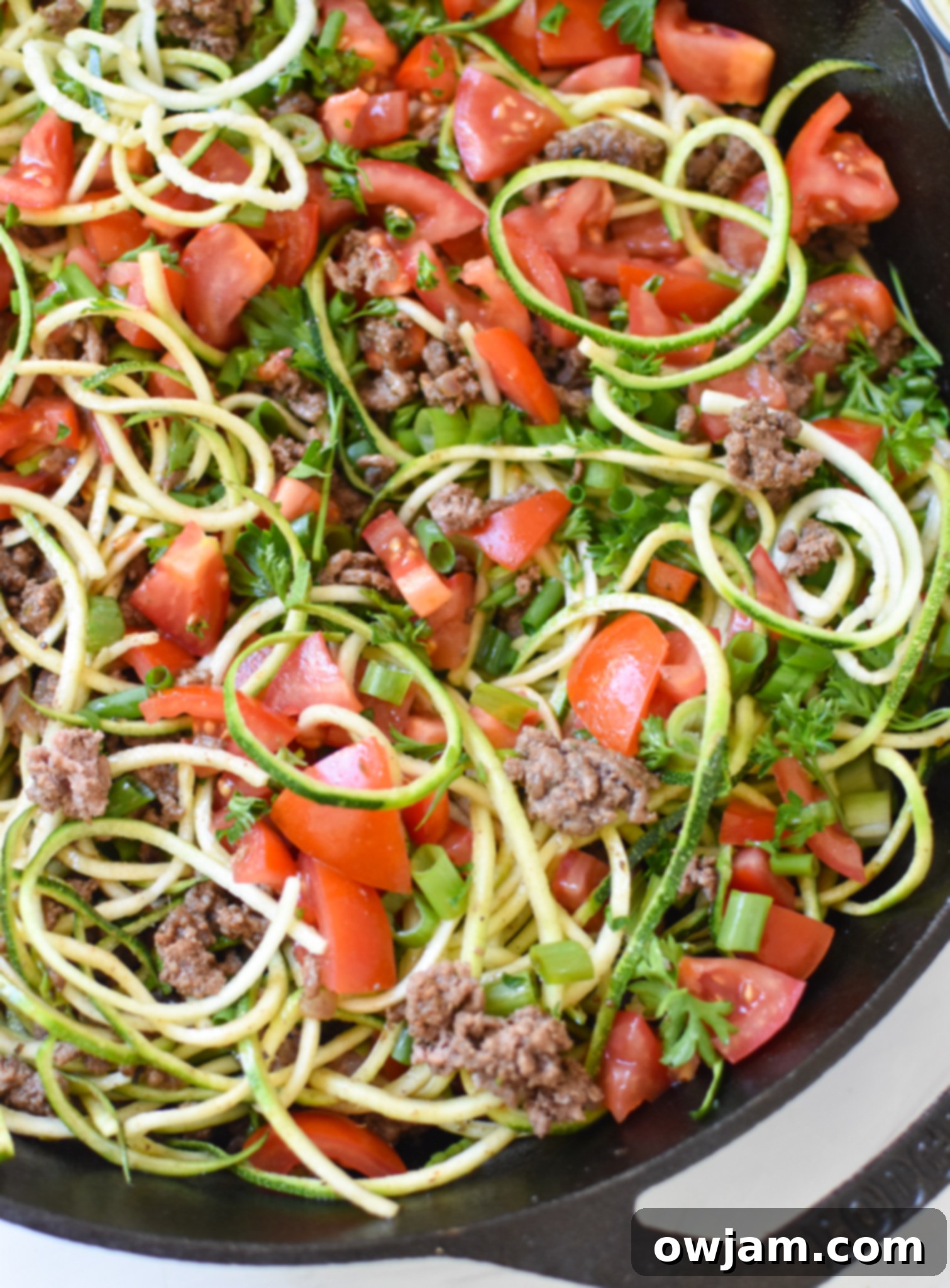 Mediterranean Ground Beef Zucchini Skillet topped with fresh tomatoes and herbs.