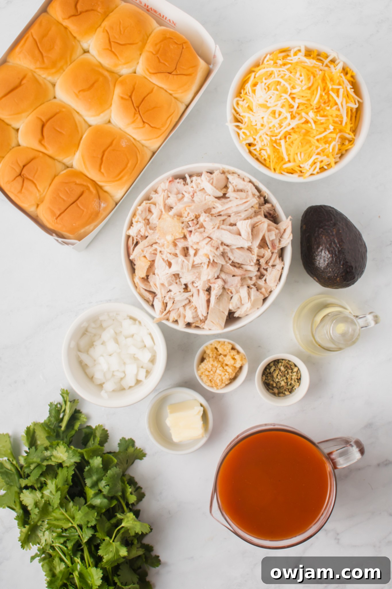 Irresistible Chicken Enchilada Sliders 3 Various ingredients laid out for Chicken Enchilada Sliders, including chicken, enchilada sauce, cheese, onions, and garlic.