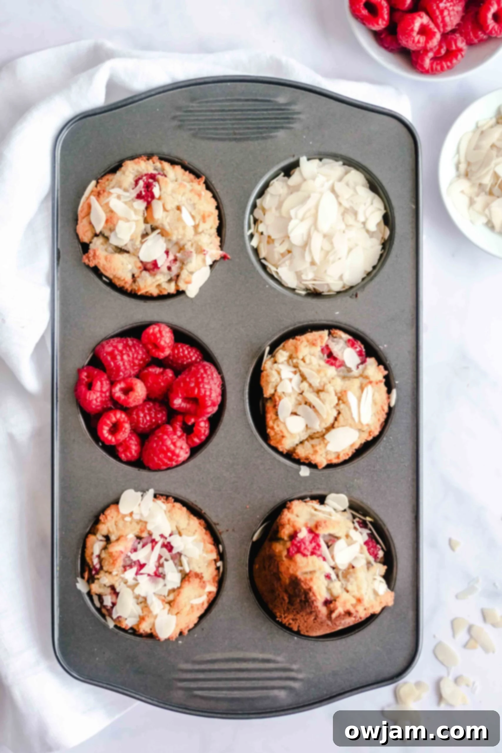 Unbaked Keto Raspberry Muffins batter in a muffin tin, ready for the oven.