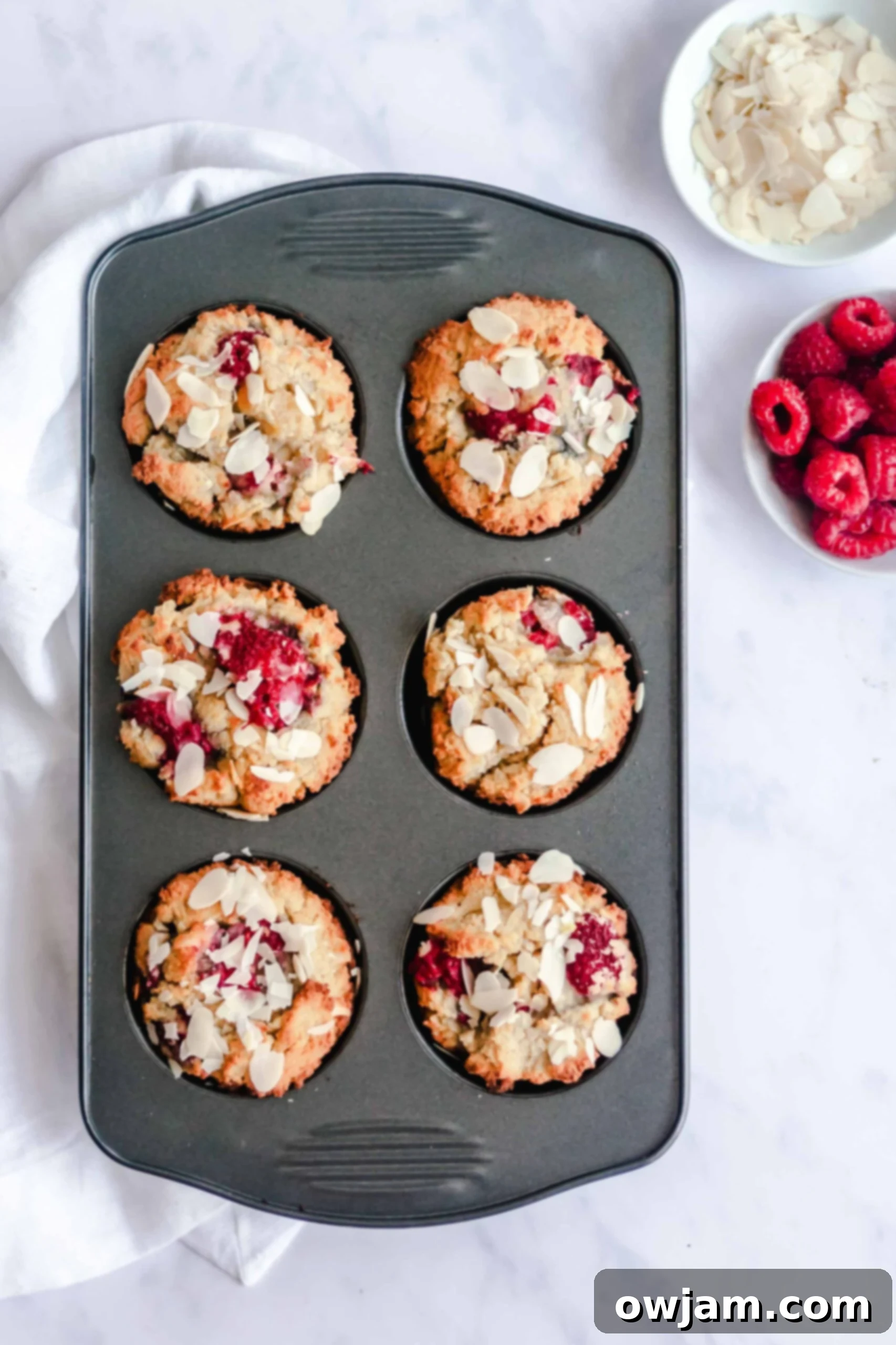 Freshly baked Keto Raspberry Muffins garnished with extra raspberries, ready to be enjoyed.