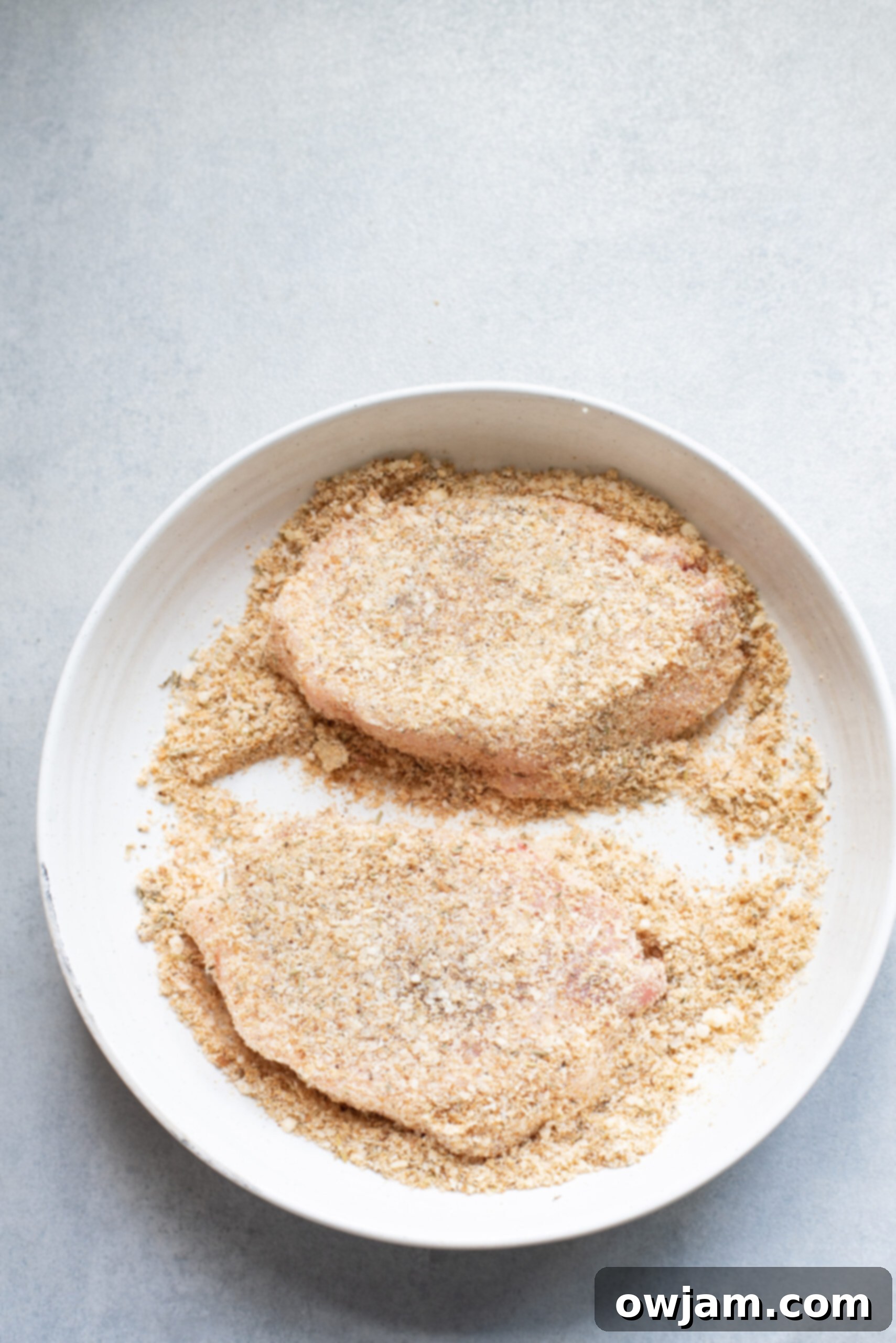 Golden Parmesan Pork Chops 6 A pork chop fully coated in the Parmesan breadcrumb mixture, ready for searing.