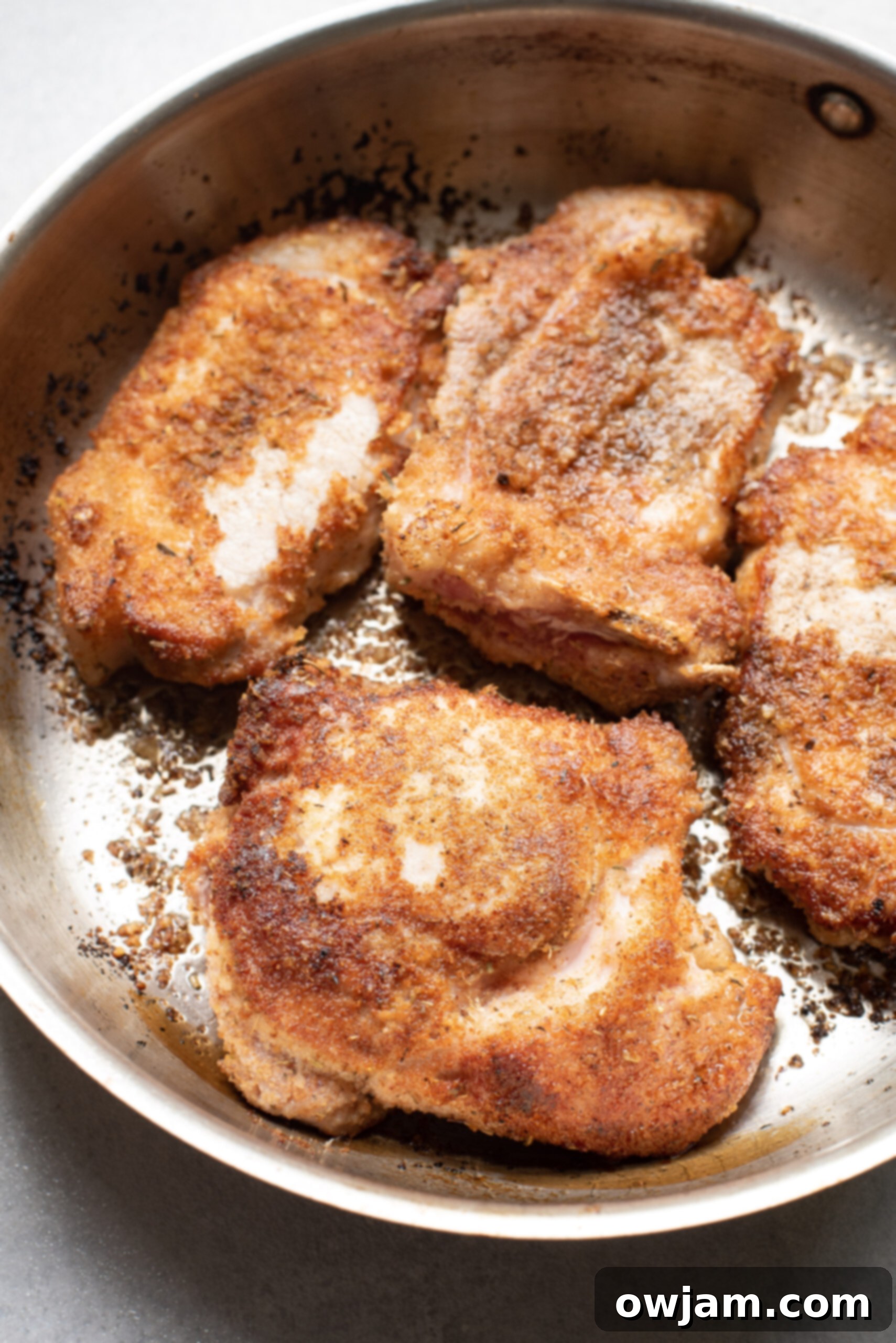 Golden Parmesan Pork Chops 7 Pork chops searing in a hot skillet, developing a golden-brown crust.