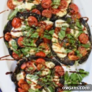 Caprese-Stuffed Portobellos 7 Caprese Stuffed Portobello Mushrooms on a white plate with a balsamic glaze drizzle.