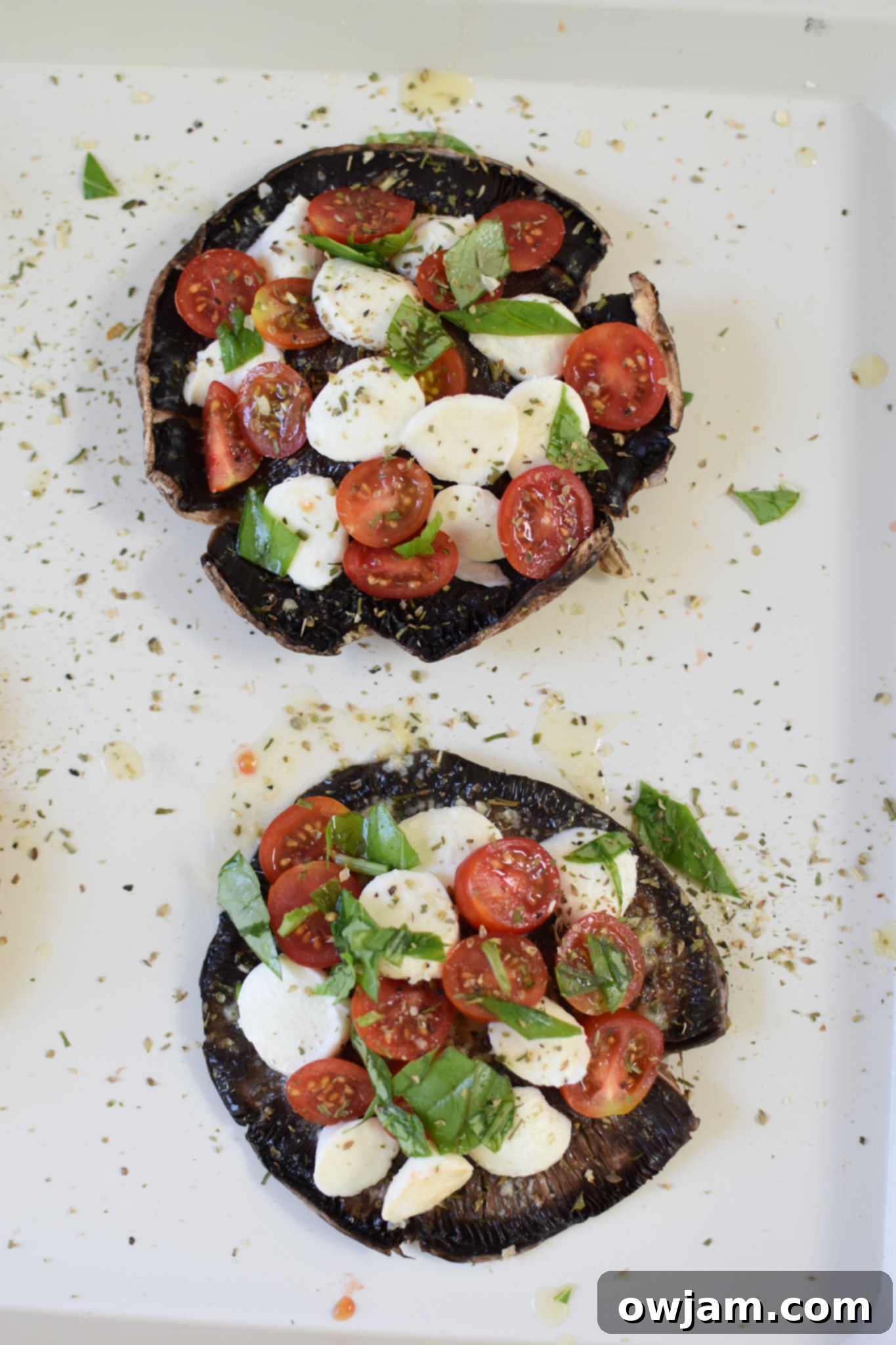 Caprese-Stuffed Portobellos 5 Prepared Caprese Stuffed Portobello Mushrooms with mozzarella and tomatoes on a baking sheet, ready for the oven.