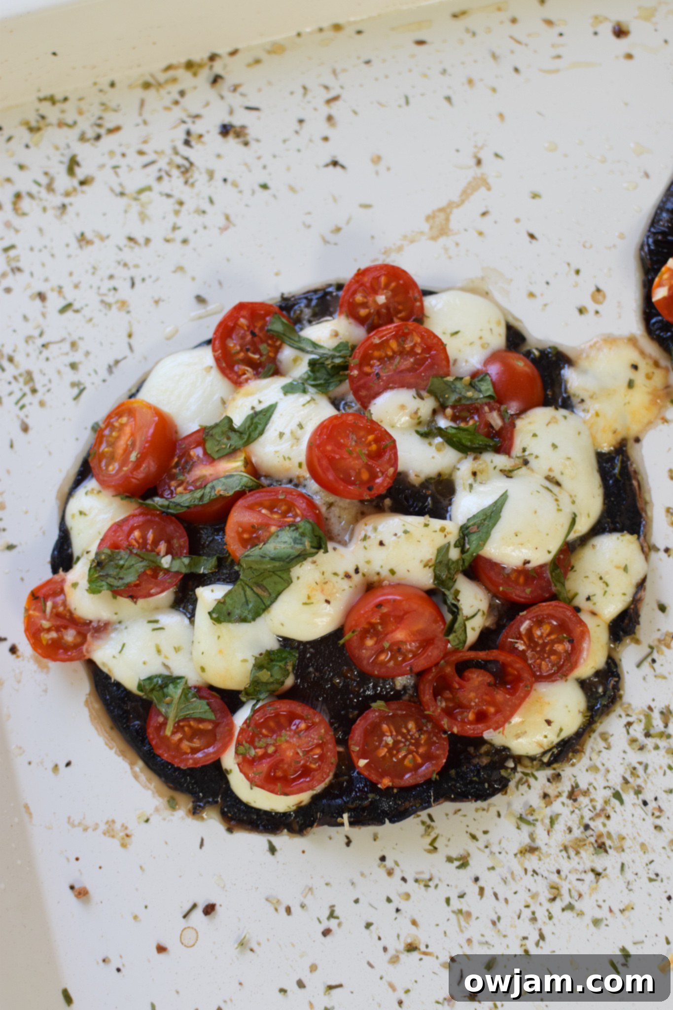Caprese-Stuffed Portobellos 6 Close-up of baked Caprese Stuffed Portobello Mushrooms on a baking sheet, showing melted cheese and cooked tomatoes.