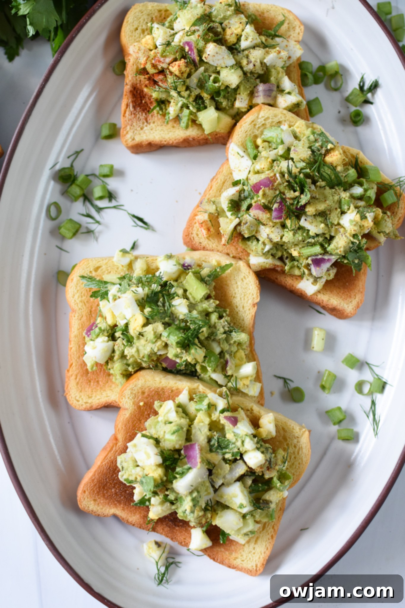 Creamy Avocado Egg Salad 4 Platter of delicious Avocado Egg Salad toasts, garnished with fresh herbs.