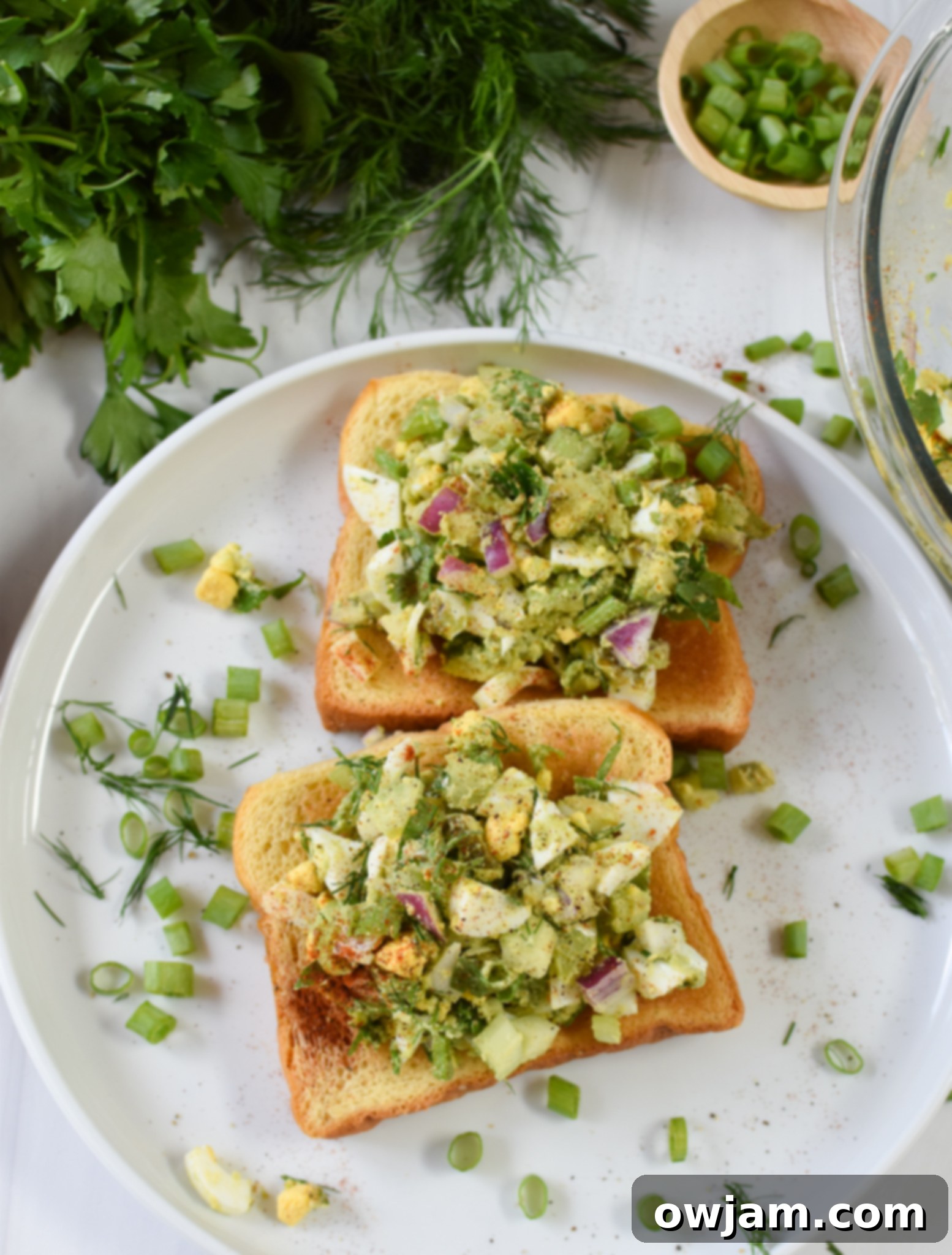 Creamy Avocado Egg Salad 7 A single serving of Avocado Egg Salad on toasted bread, presented on a clean white plate.
