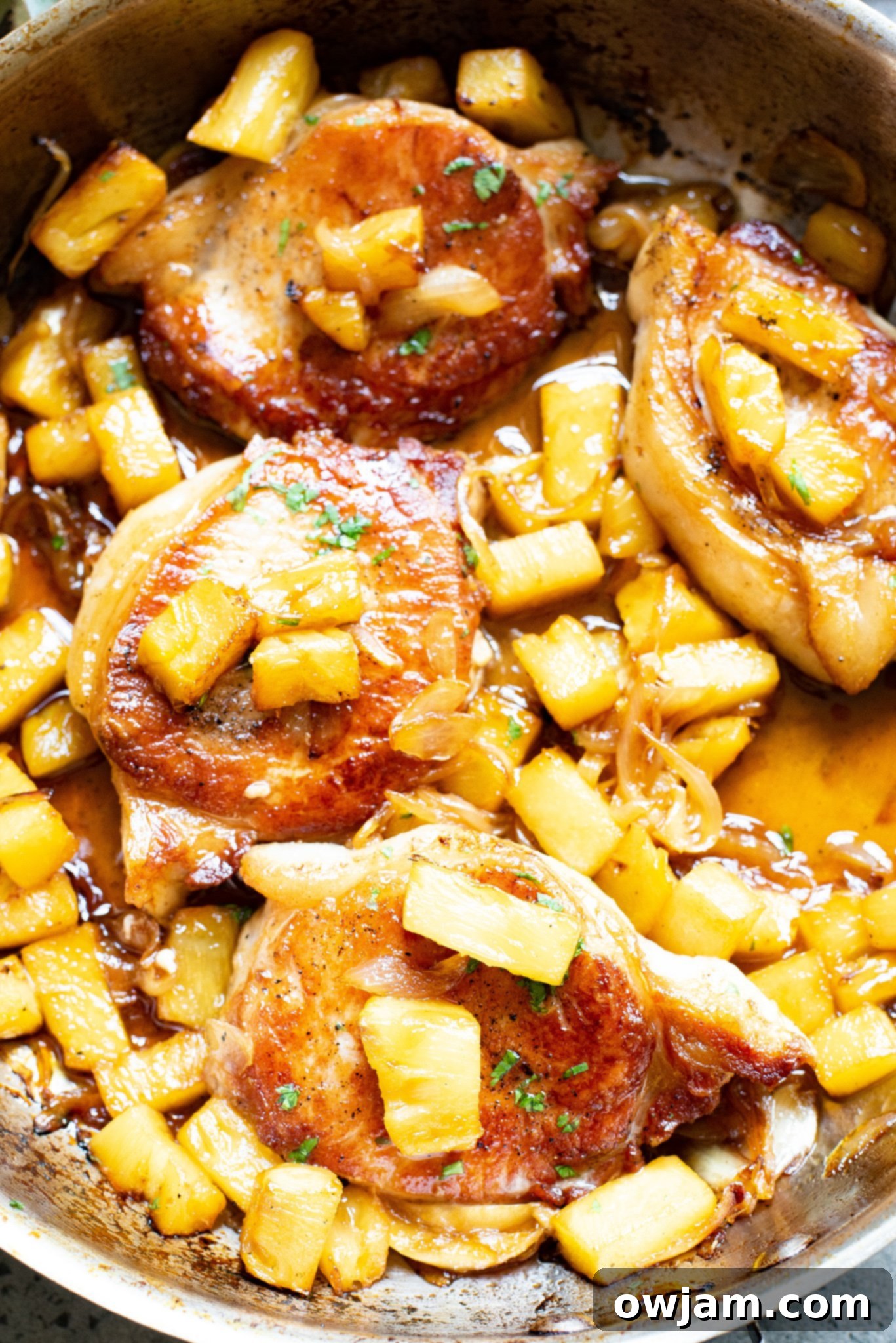 Sweet and Savory Pineapple Pork Chops 2 Juicy Easy Pineapple Pork Chops served in a skillet, garnished with fresh herbs, ready to eat.