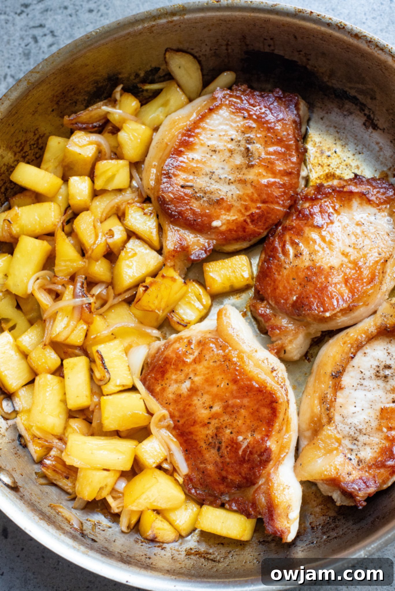 Sweet and Savory Pineapple Pork Chops 7 Easy pineapple pork chops cooked in a skillet, coated in a sweet and sour sauce, garnished with fresh cilantro.