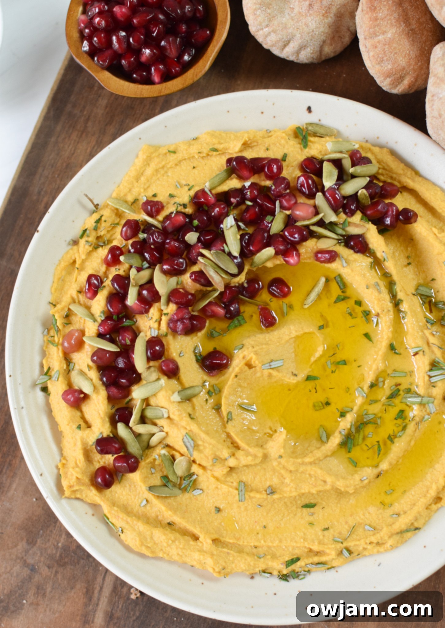 Velvet Pumpkin Dip 4 Creamy Pumpkin Hummus in a bowl, garnished with fresh pomegranate seeds, a perfect fall appetizer.