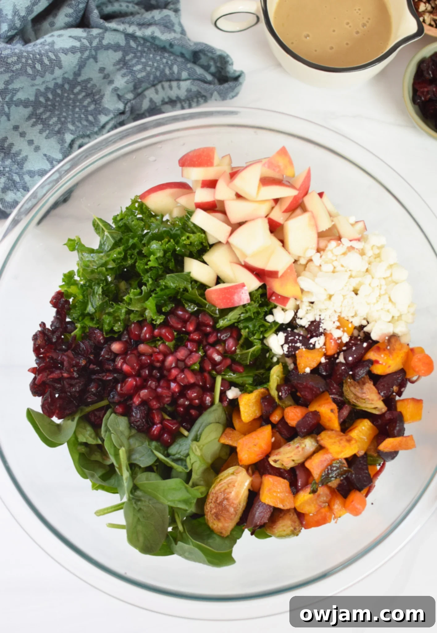 Autumn Bounty Bowl 8 Fresh kale, spinach, diced apple, pecans, dried cranberries, pomegranate arils, and goat cheese in a large salad bowl, ready for the roasted vegetables and dressing.
