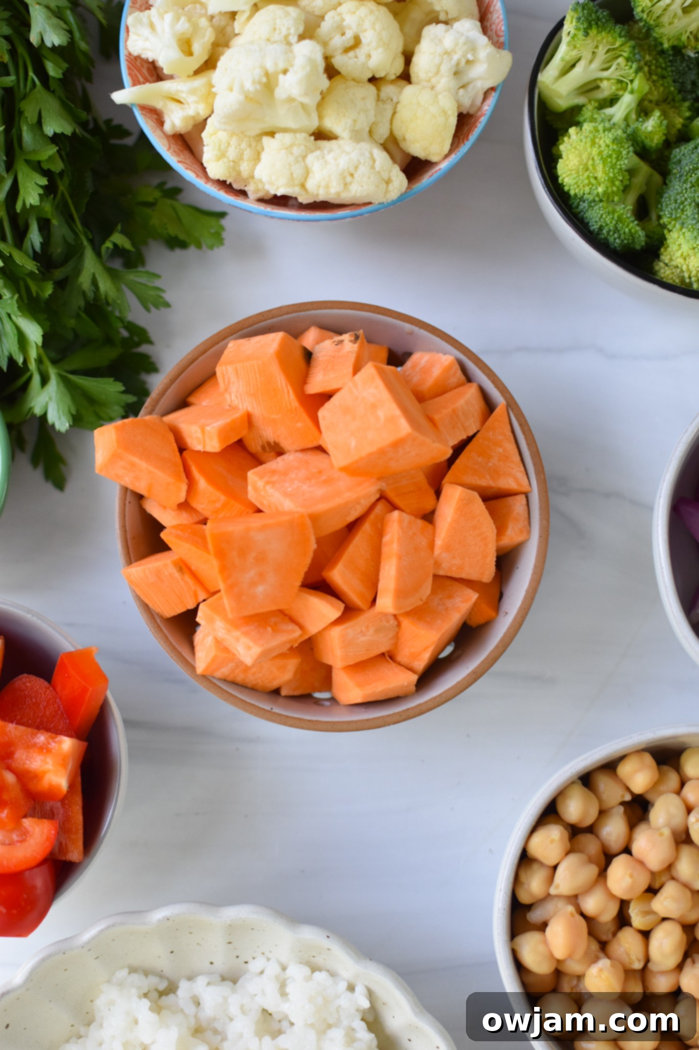 Individual ingredients laid out for a Sweet Potato Bowl, showcasing fresh vegetables, chickpeas, and tahini.