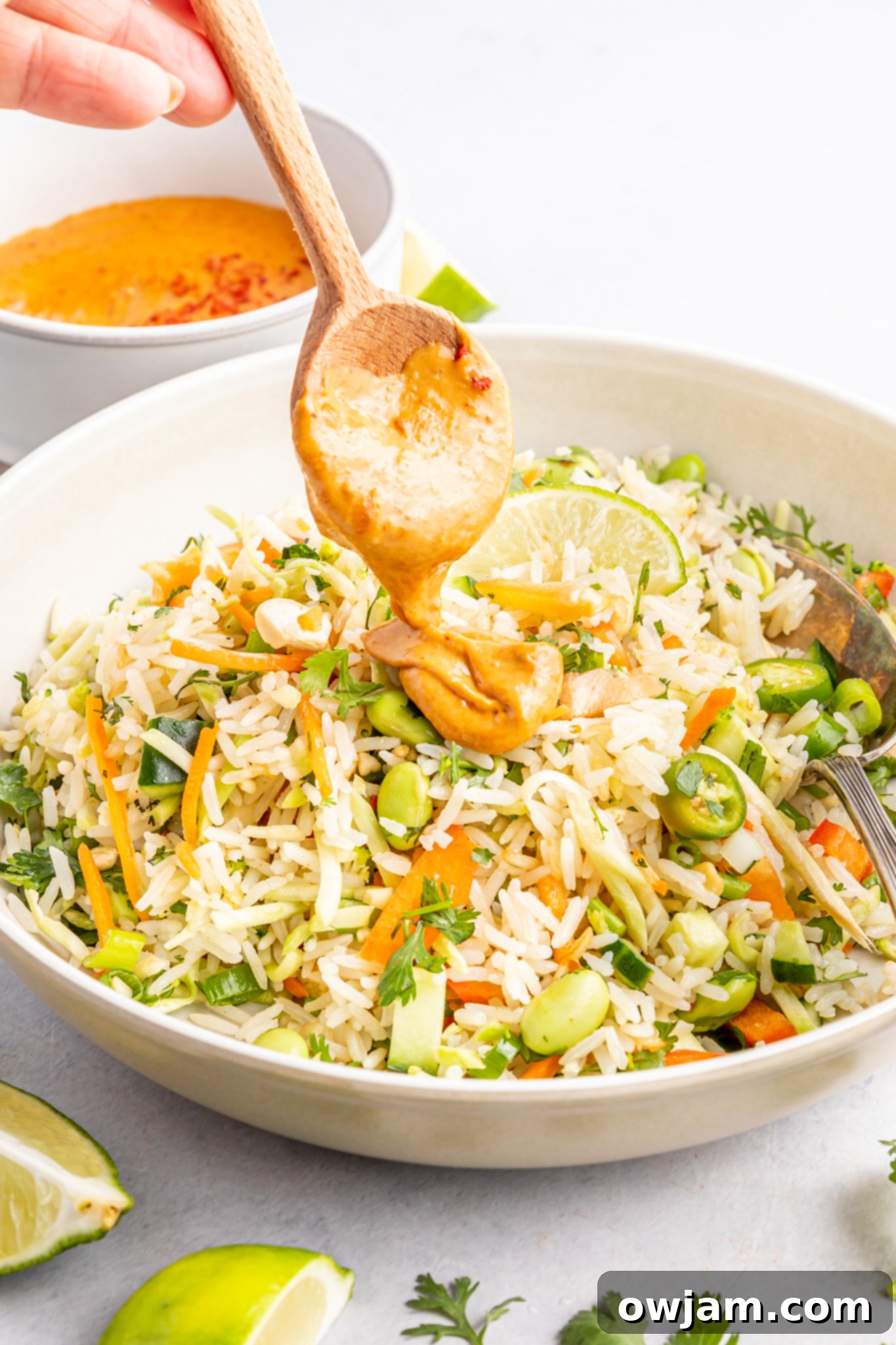 Tropical Coconut Rice Salad 5 Creamy peanut dressing being drizzled over Coconut Rice Salad.