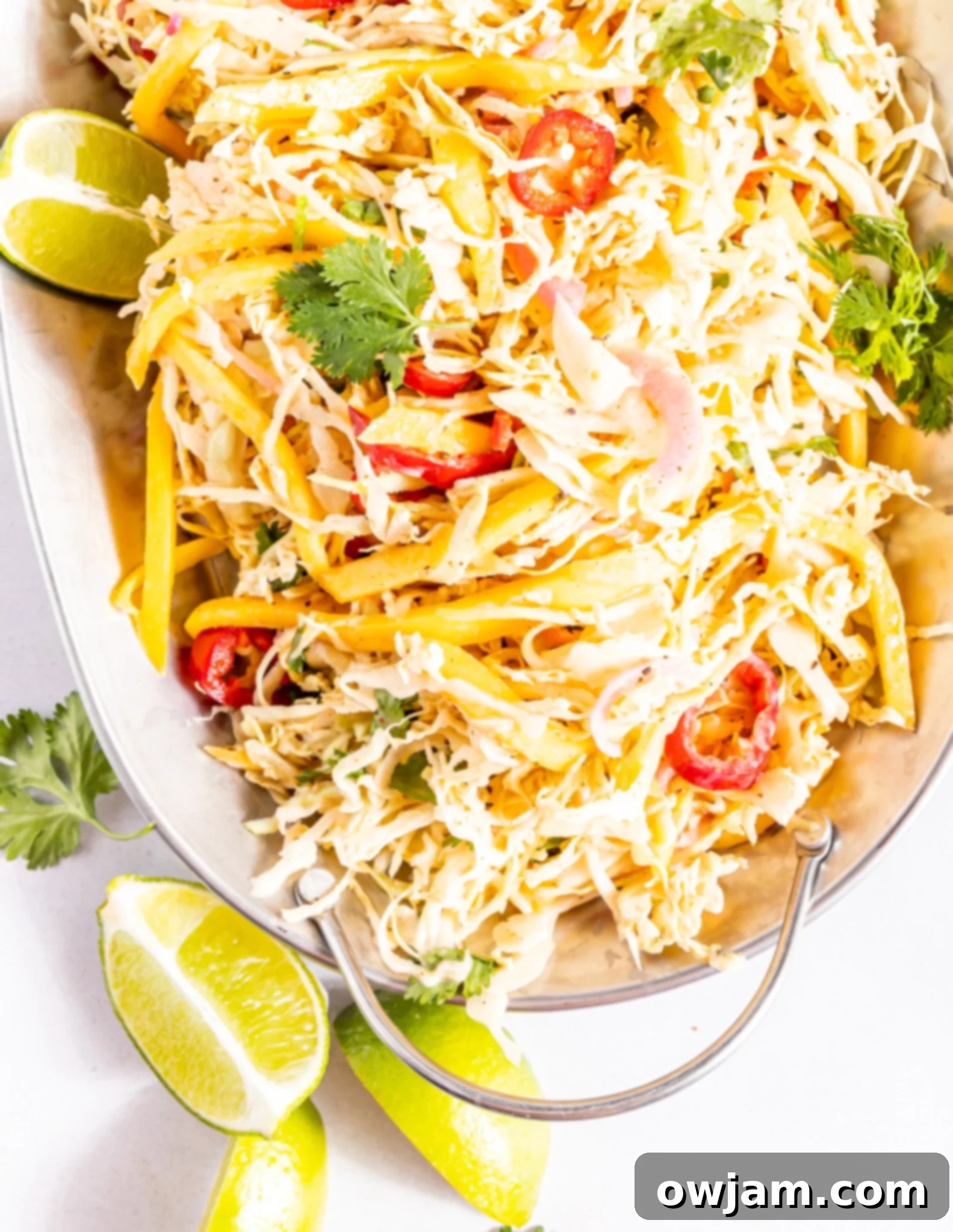 Easy Caribbean Coleslaw Recipe on a white platter, garnished with fresh herbs.