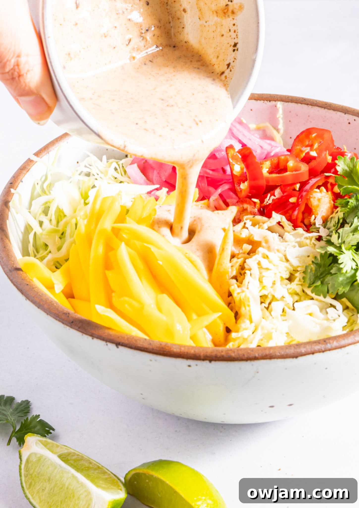 Easy Caribbean Coleslaw Recipe with dressing drizzled over the ingredients.