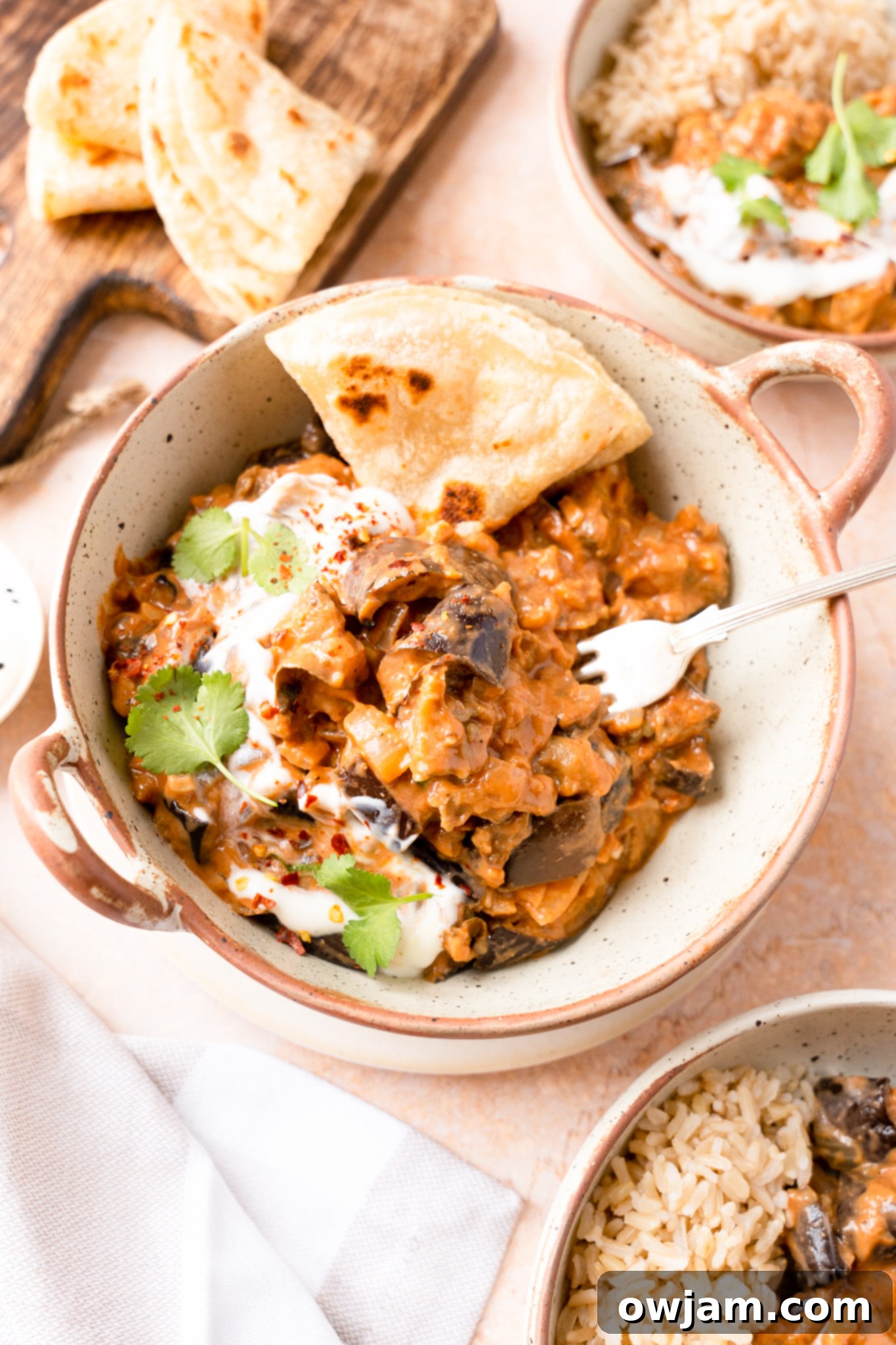Easy Eggplant Curry in a white bowl with a fork, garnished with fresh cilantro.