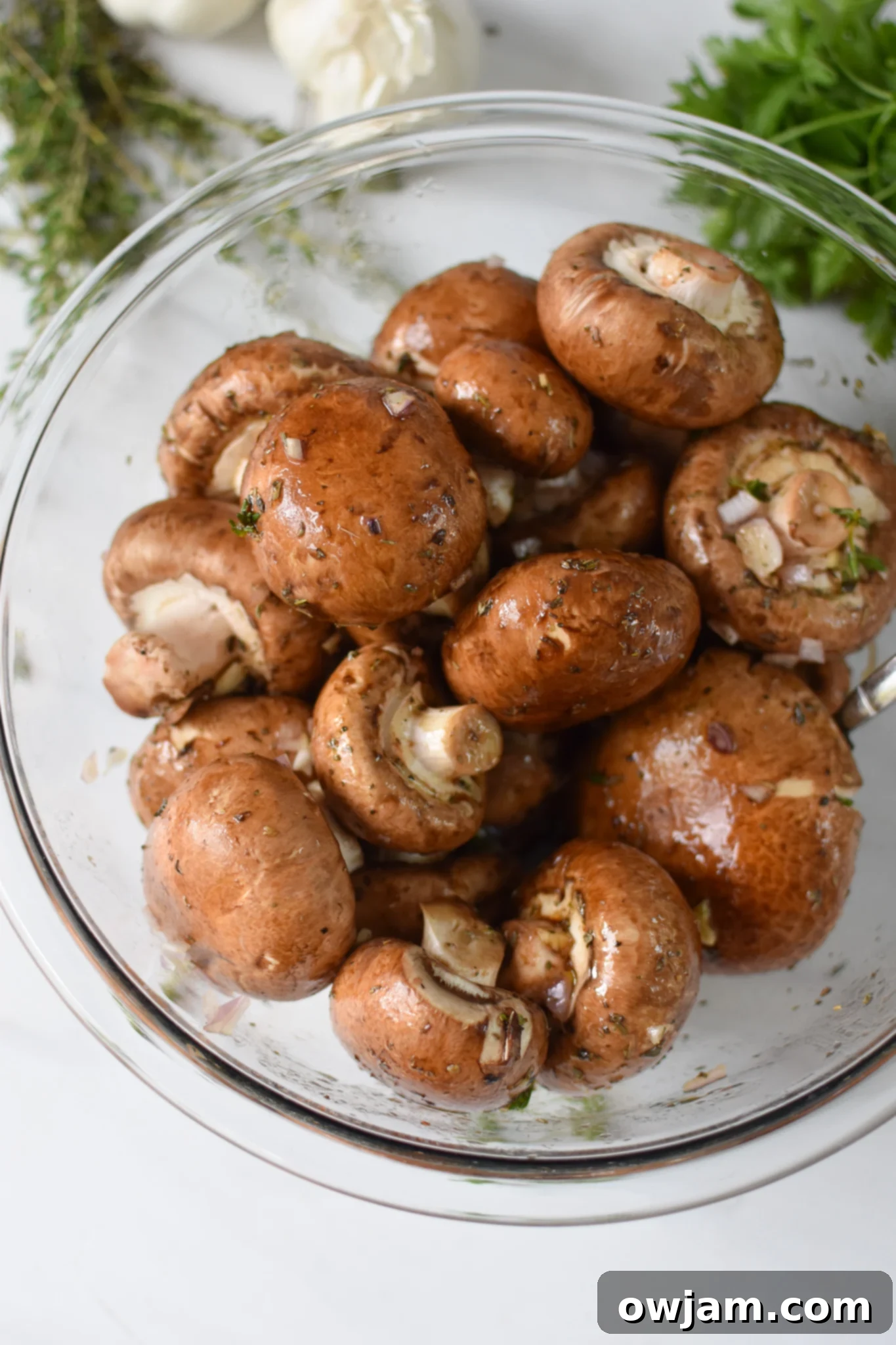 Flavorful Balsamic Roasted Mushrooms 5 Washed and cleaned mushrooms mixed with minced garlic and shallots in a clear mixing bowl.