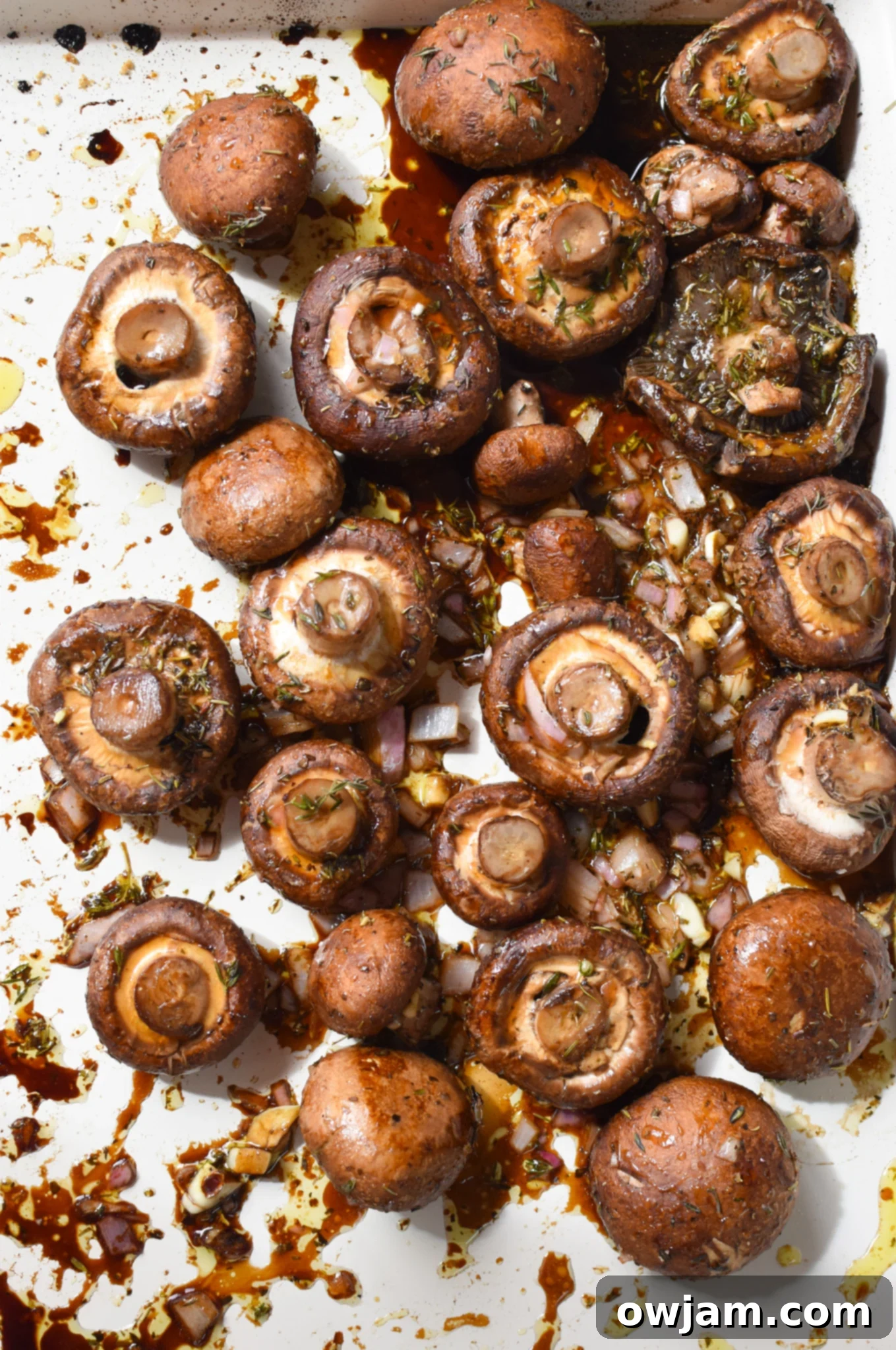 Flavorful Balsamic Roasted Mushrooms 7 Freshly roasted balsamic mushrooms on a baking sheet, garnished with fresh herbs.