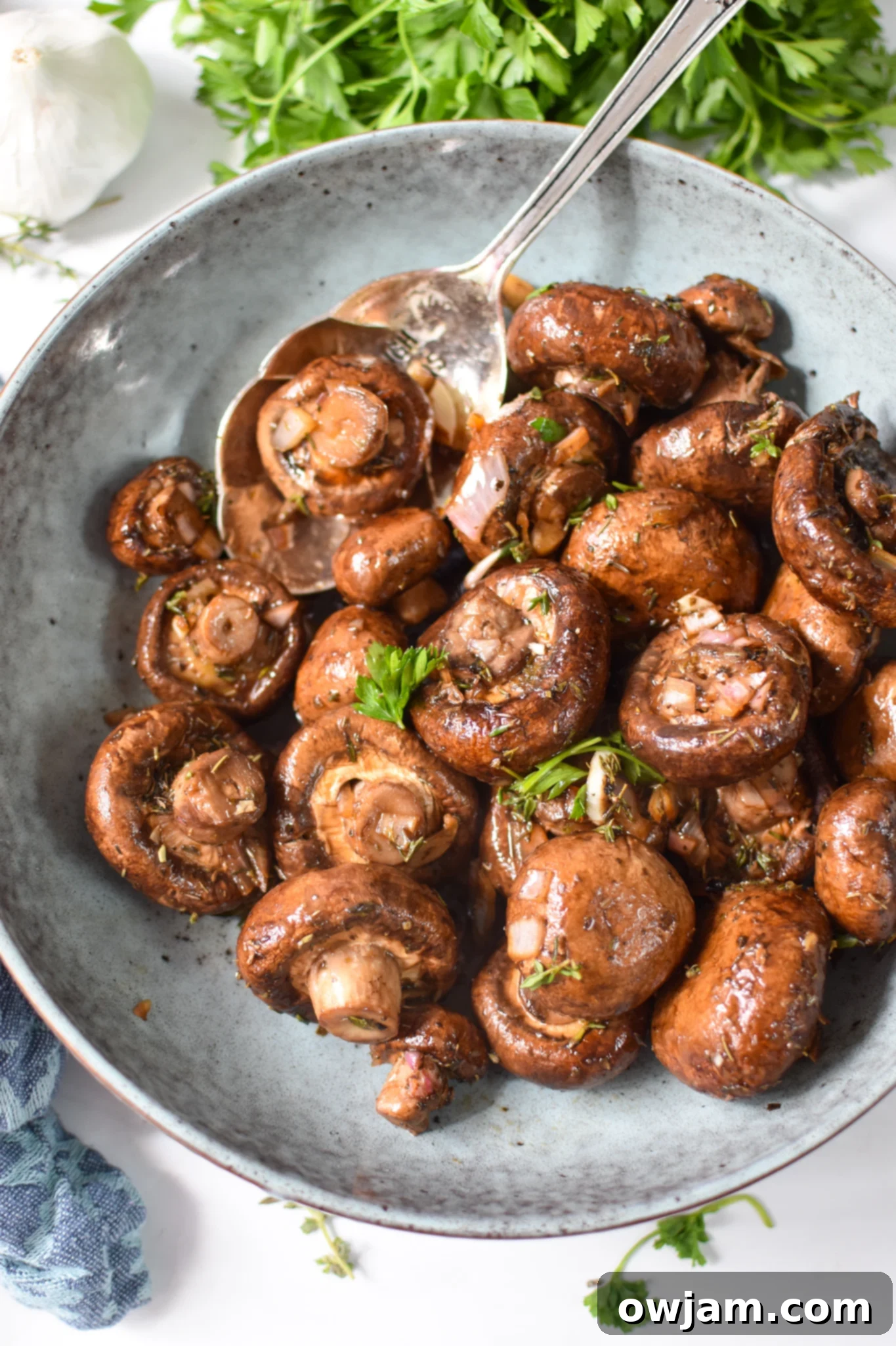 Flavorful Balsamic Roasted Mushrooms 8 Serving of roasted balsamic mushrooms in a blue bowl with fresh herbs, ready to be served.