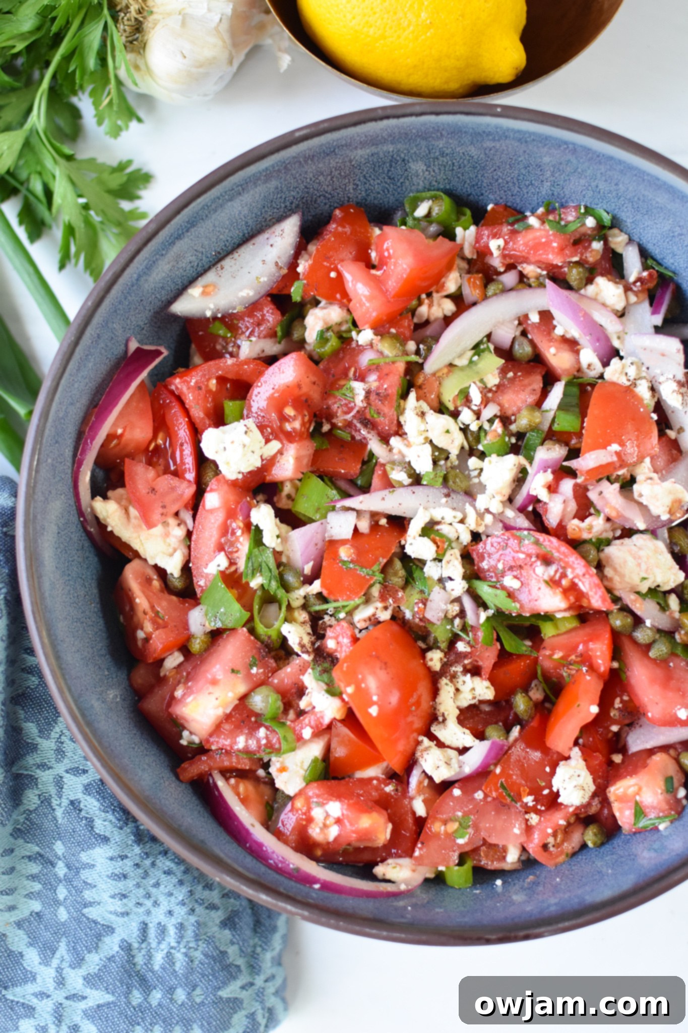 Quick and Fresh Tomato Salad 2 Easy Tomato Salad in a blue bowl, garnished with fresh herbs.