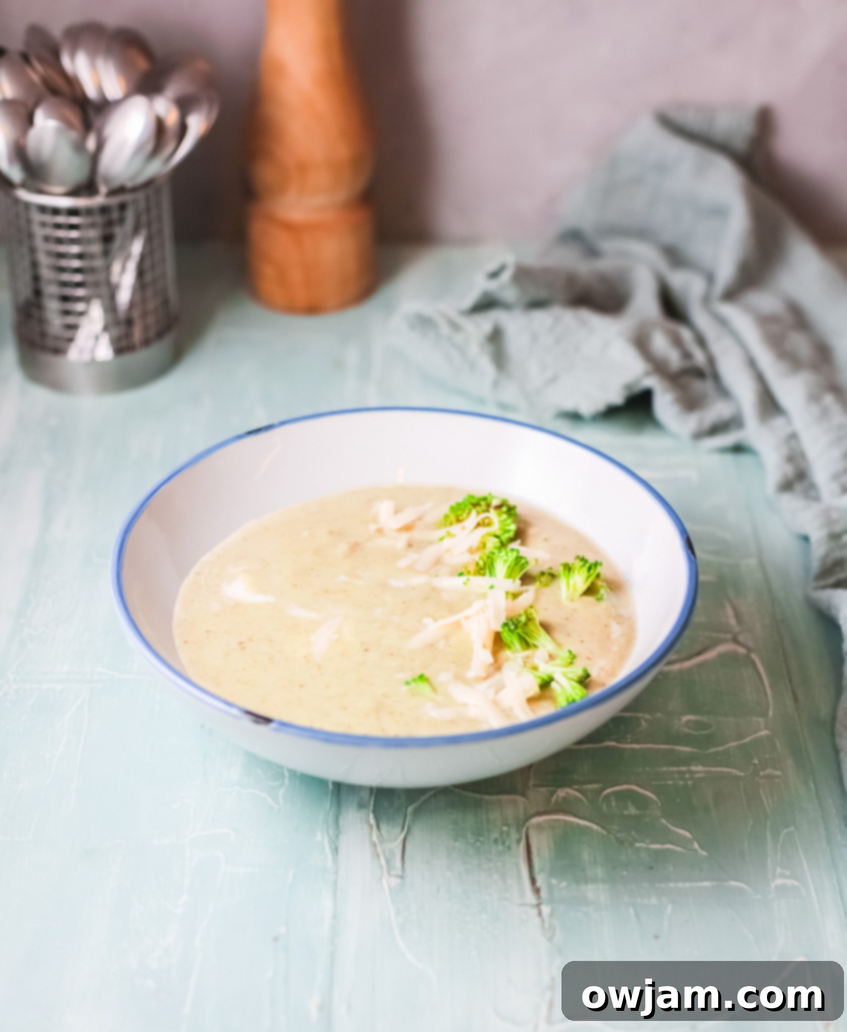 Creamy Instant Pot Broccoli Soup 3 A selection of fresh ingredients laid out on a blue background, including broccoli florets, onion, garlic, and cheese, ready for Instant Pot Broccoli Soup.