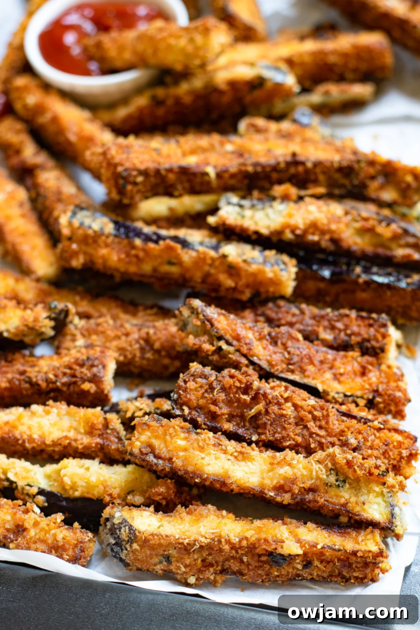 Crispy Air Fryer Eggplant Fries 2 Crispy Air Fryer Eggplant Fries cooling on parchment paper after cooking.