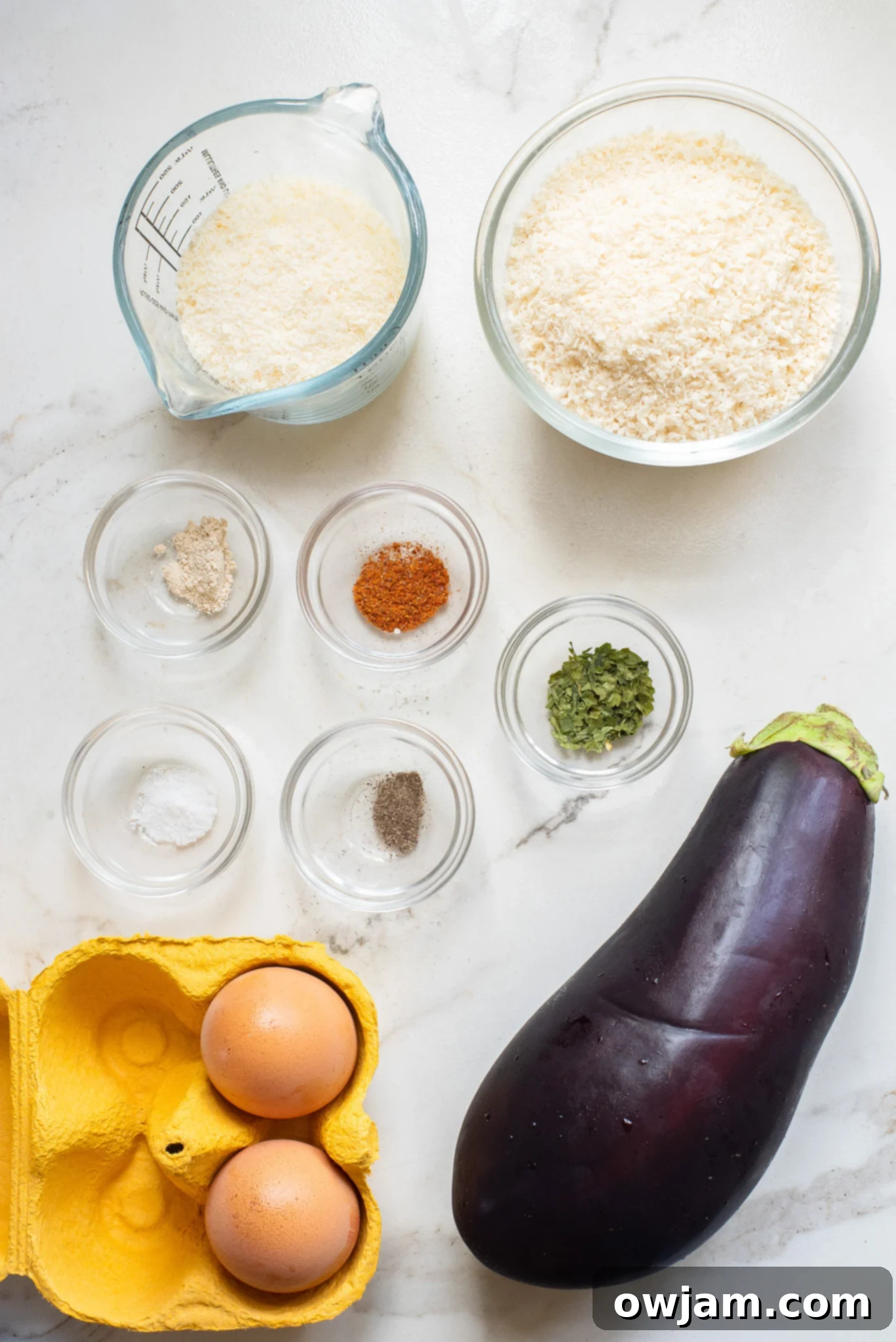 Crispy Air Fryer Eggplant Fries 3 A selection of fresh ingredients laid out, including eggplant, panko breadcrumbs, Parmesan cheese, herbs, and eggs, for making Air Fryer Eggplant Fries.