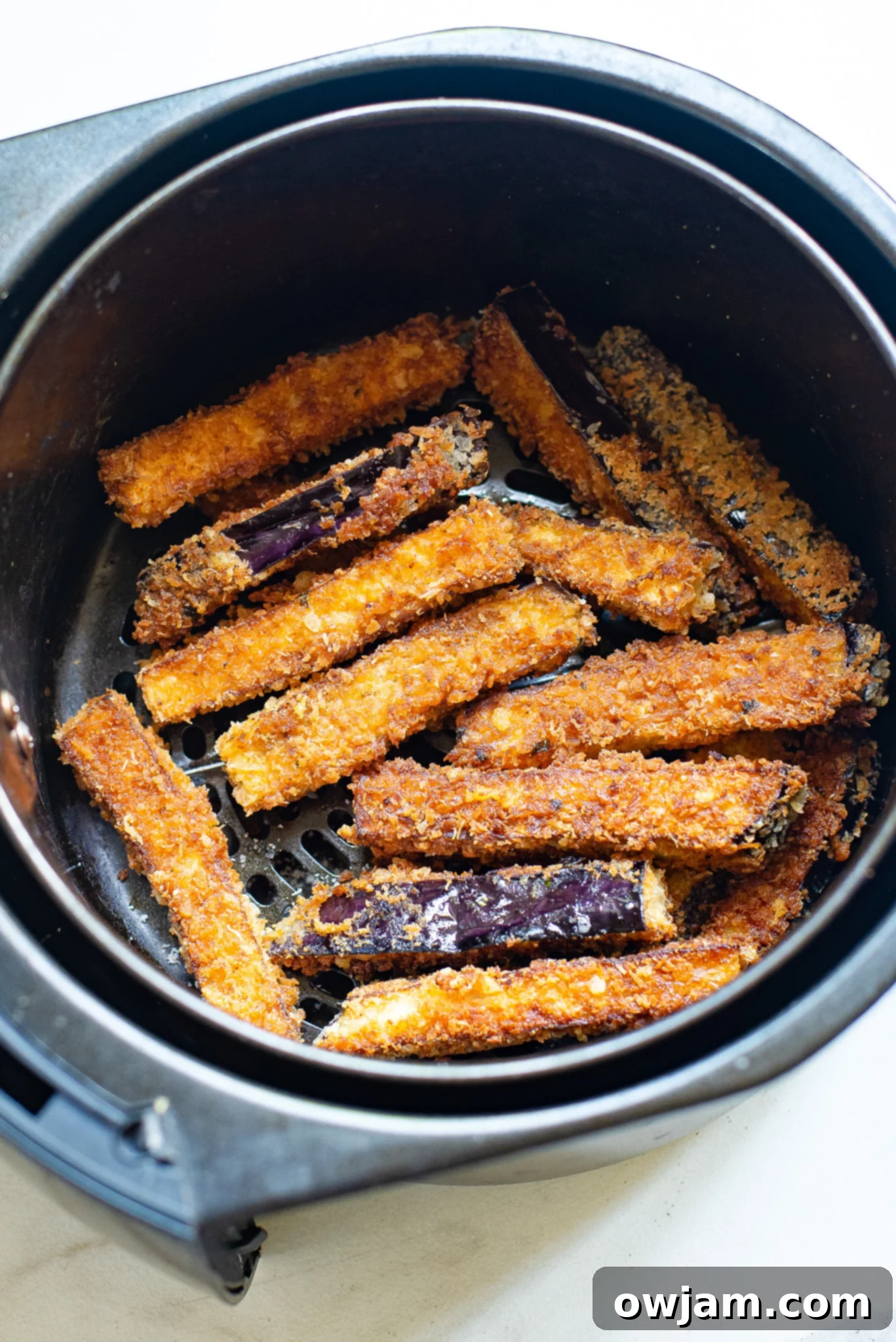 Crispy Air Fryer Eggplant Fries 8 Crispy Air Fryer Eggplant Fries cooking in an air fryer basket, turning golden brown.