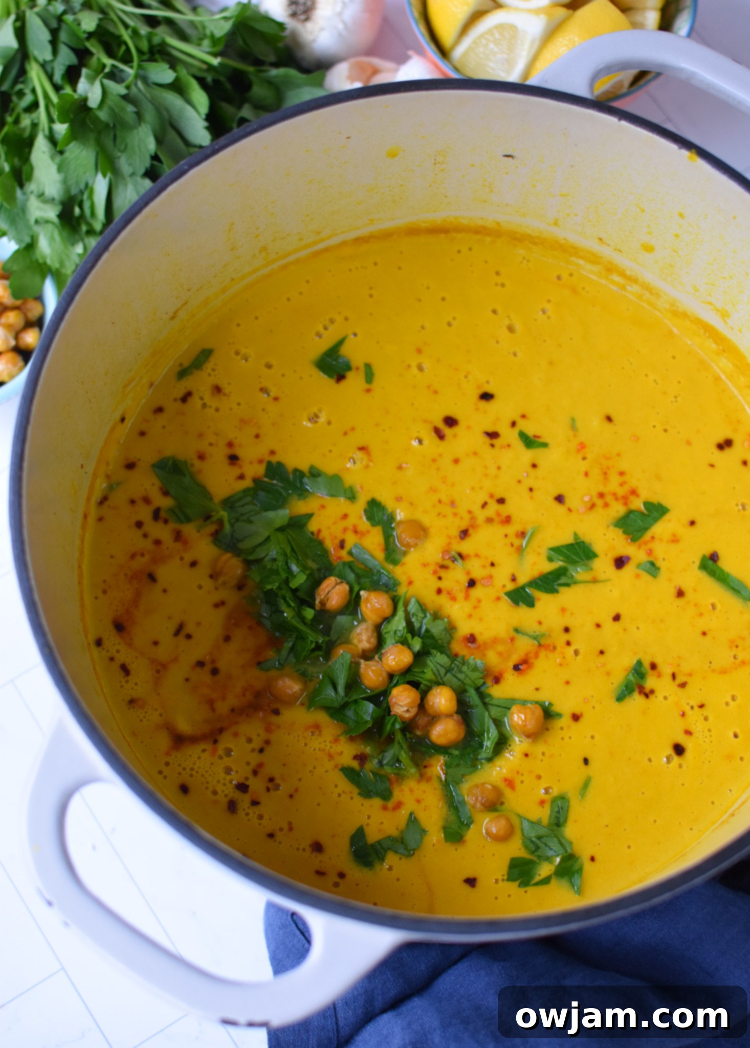 Velvety Roasted Cauliflower Soup 4 A large pot on a stove, with sautéed vegetables and cauliflower beginning to simmer for creamy cauliflower soup.