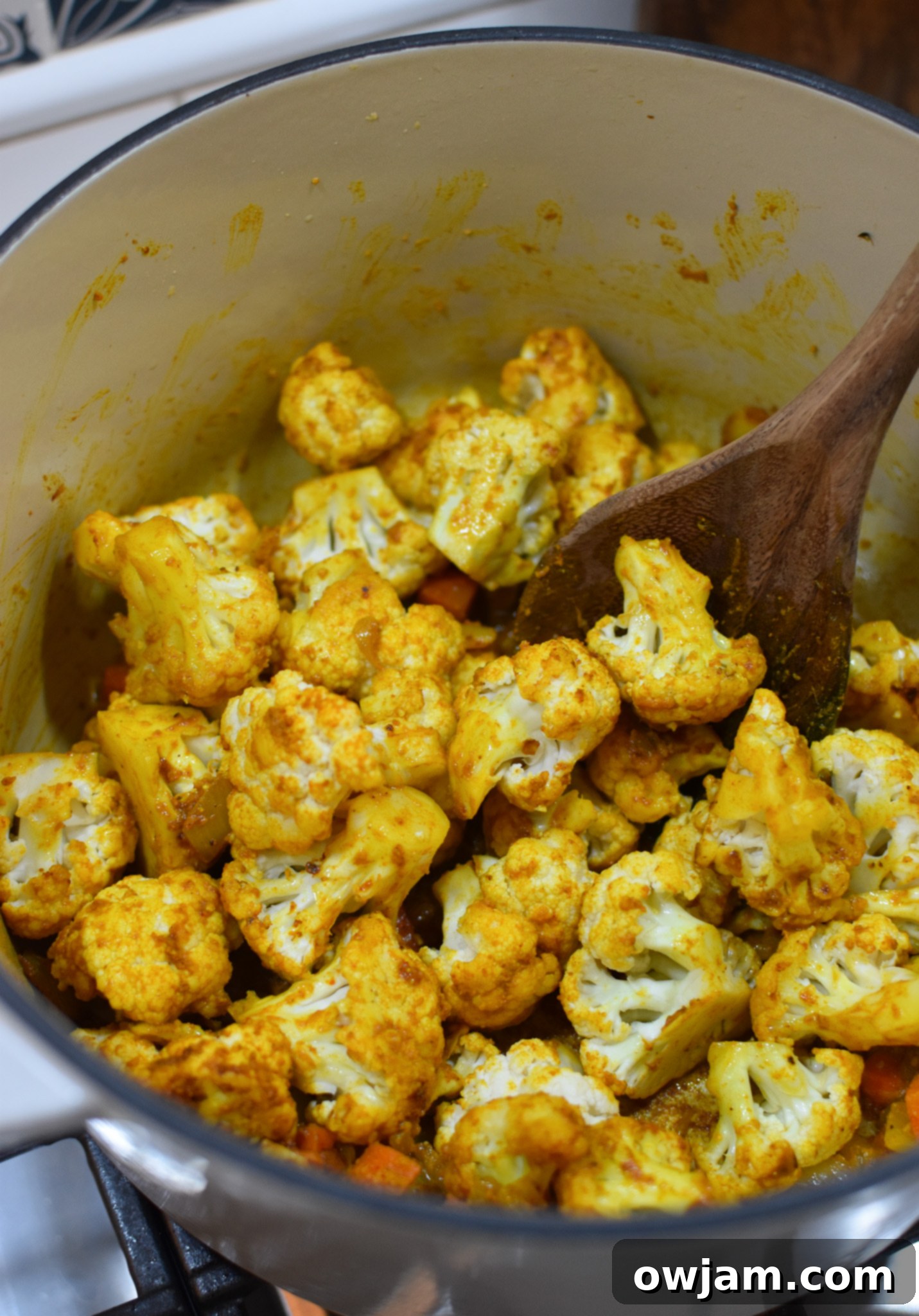 Cauliflower florets added to the pot with sautéed vegetables, ready to be simmered for creamy cauliflower soup.