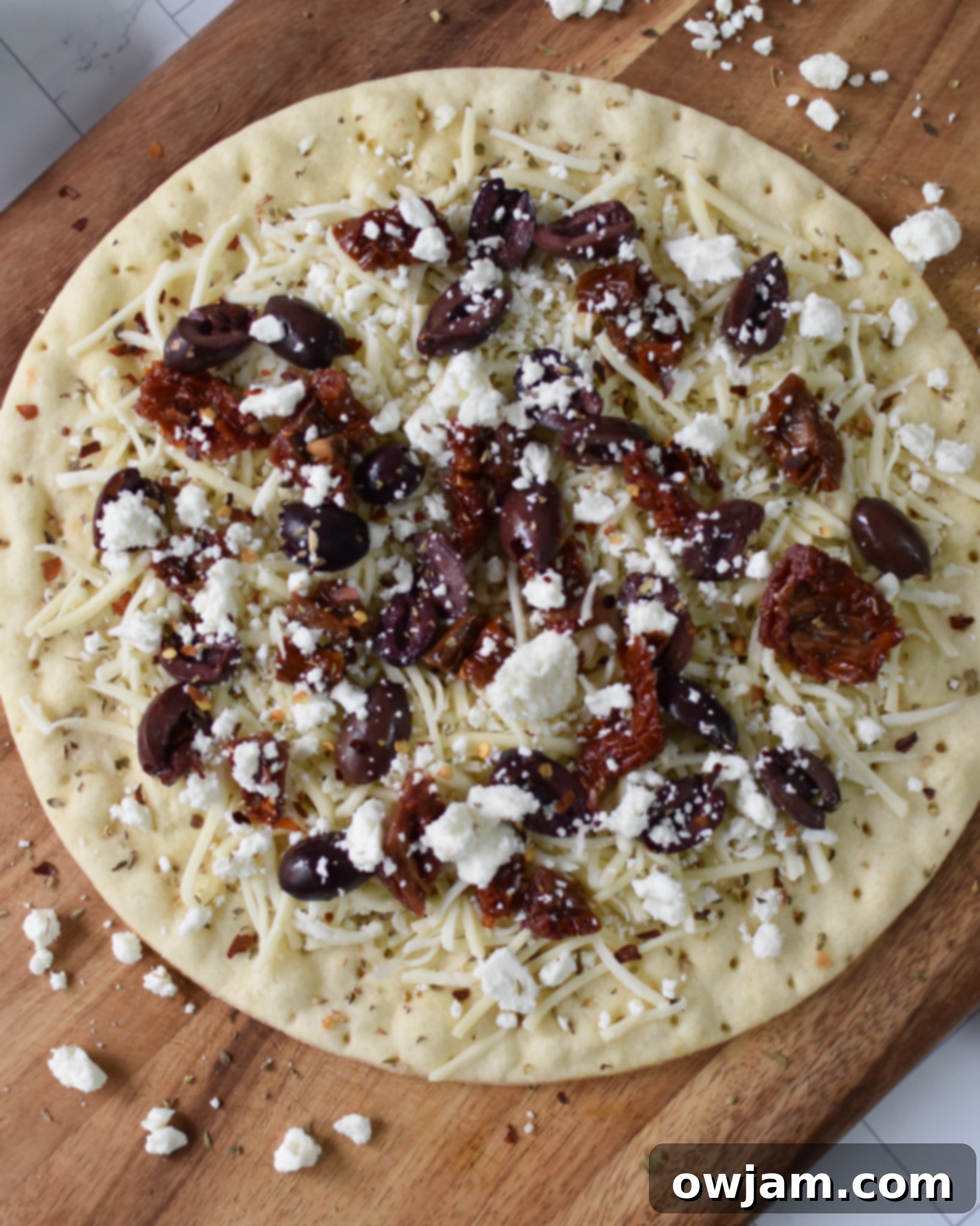 Greek Pizza with cheese and sun-dried tomatoes on it.