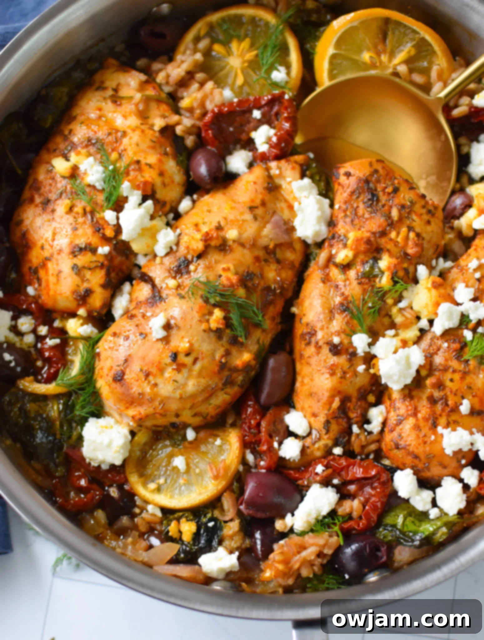 A golden spoon scooping a portion of Sun-dried Tomato Farro Chicken Bake from a baking dish.