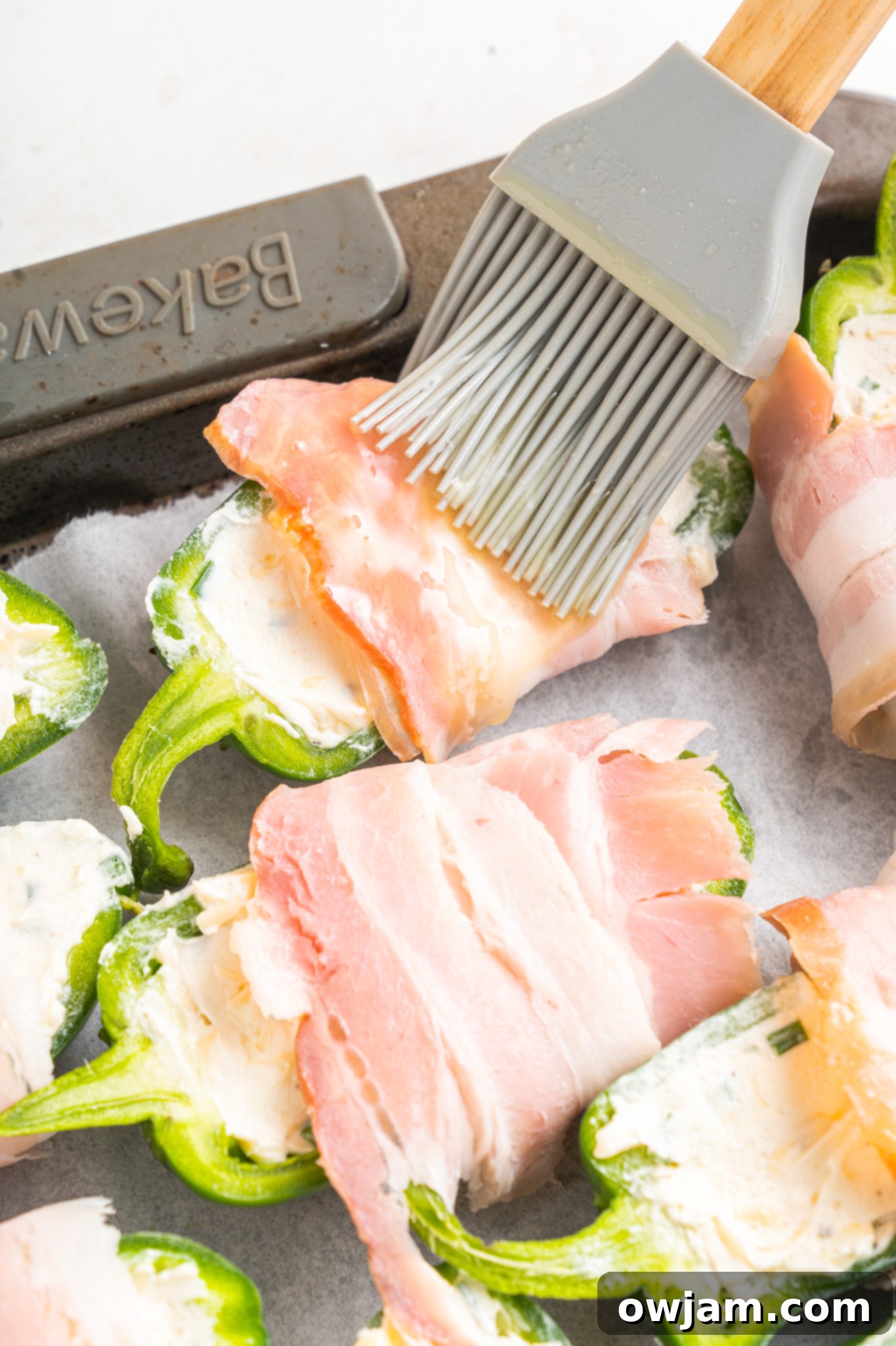 Jalapeño Poppers with Bacon brushing bacon with glaze. 