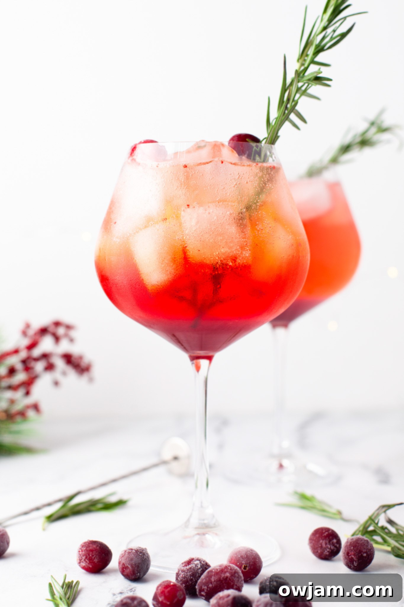 Cranberry Aperol Spritz with a sprig of rosemary and floating cranberries.