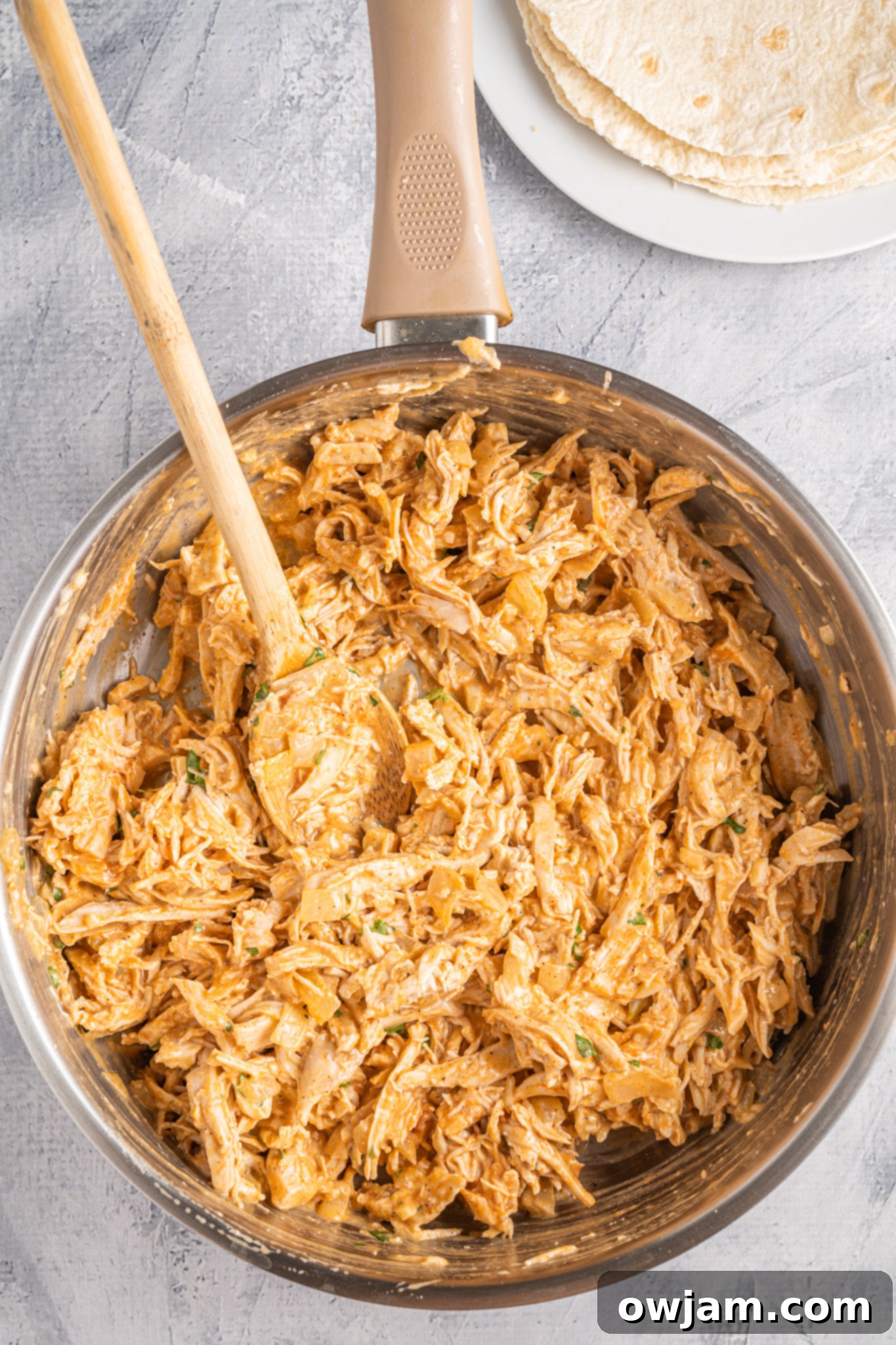 Spicy Cheesy Buffalo Chicken Quesadillas 7 Shredded chicken fully mixed with buffalo sauce, ranch, and herbs in a skillet, creating the quesadilla filling.
