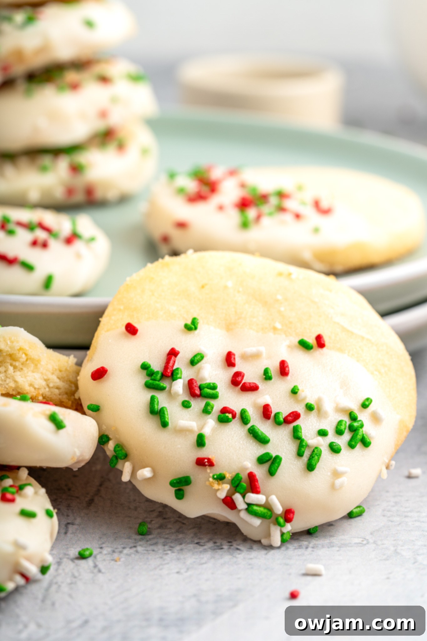 Christmas Shortbread Cookies on a green plate, beautifully decorated with white chocolate and festive sprinkles, ready to be enjoyed during the holiday season.