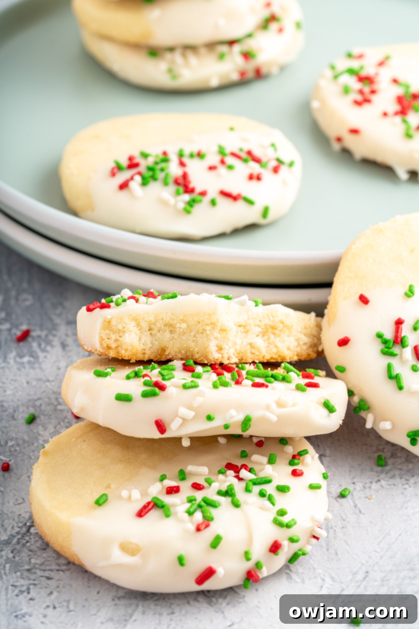 A collection of Christmas Shortbread Cookies, beautifully frosted with white chocolate and adorned with colorful sprinkles, ready for the holidays.