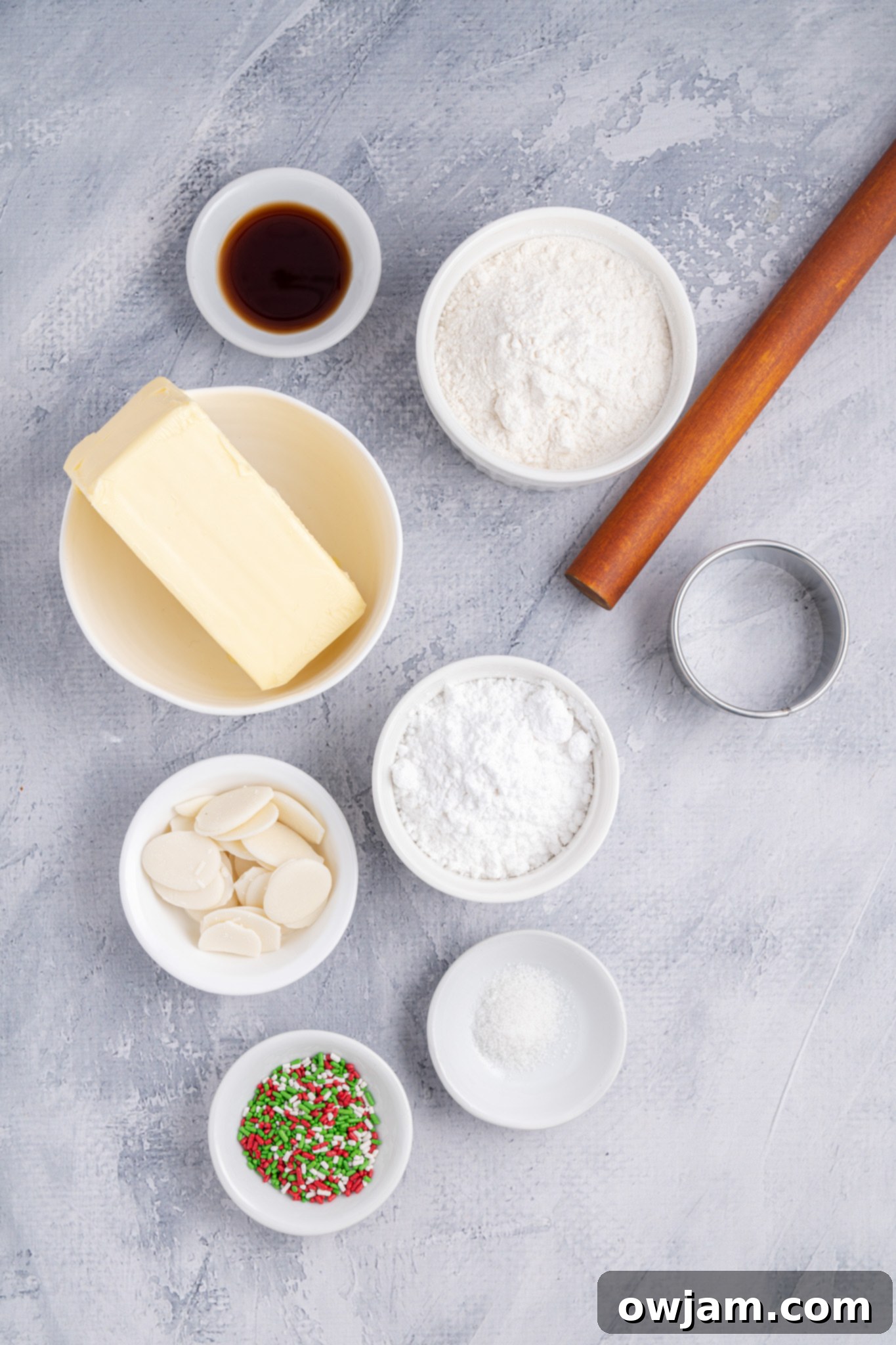 All the essential ingredients for Christmas Shortbread Cookies laid out, including butter, powdered sugar, vanilla extract, and flour.