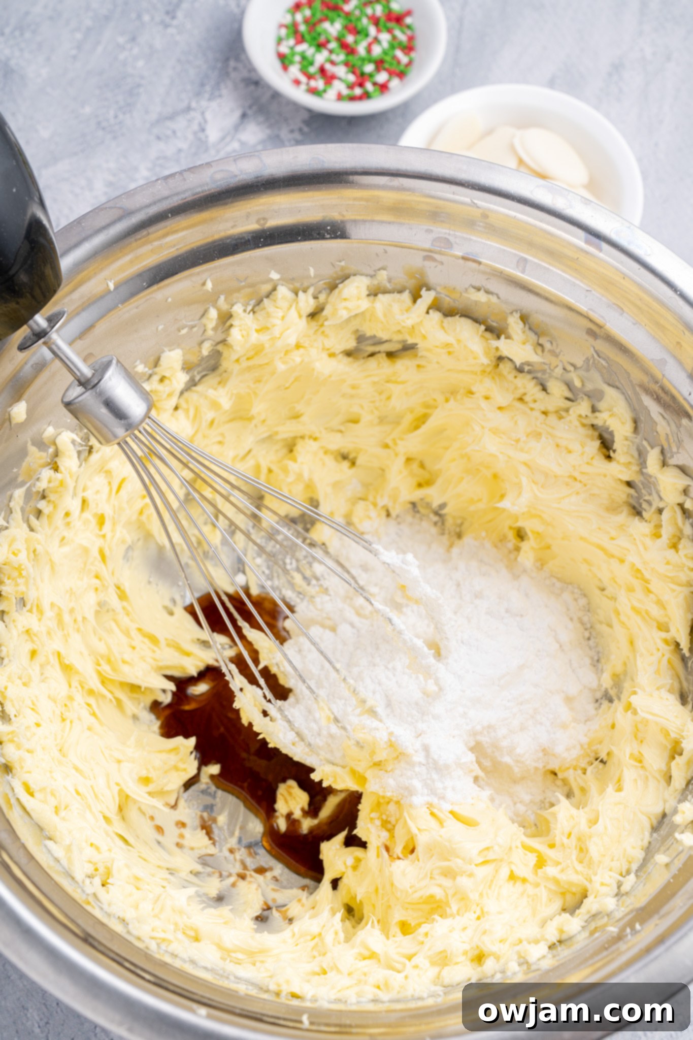 Close-up of butter, powdered sugar, and vanilla extract being mixed in a bowl for Christmas Shortbread Cookies.