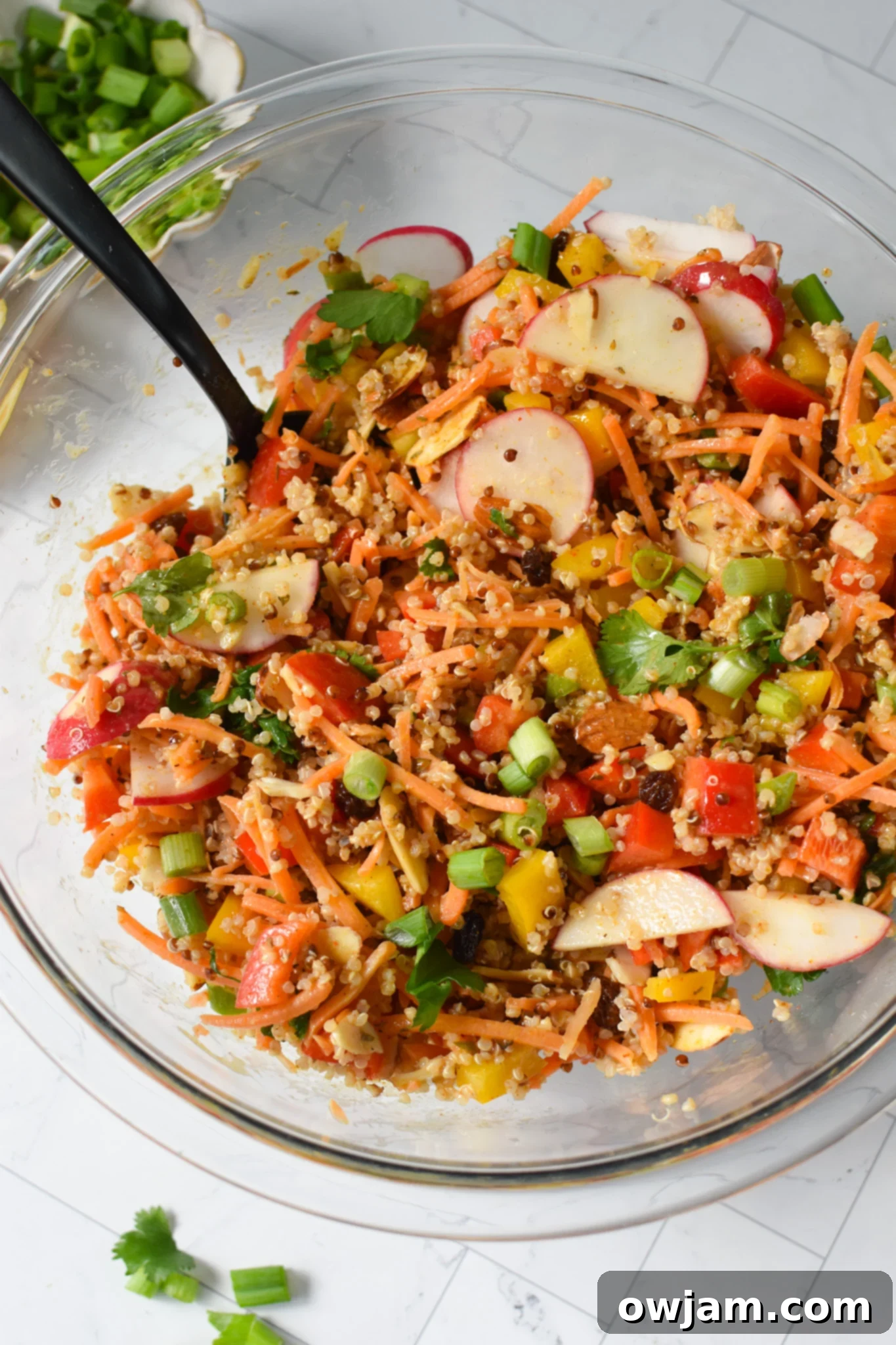 The Curried Quinoa Salad fully mixed with its vibrant dressing, ready to be served or stored.