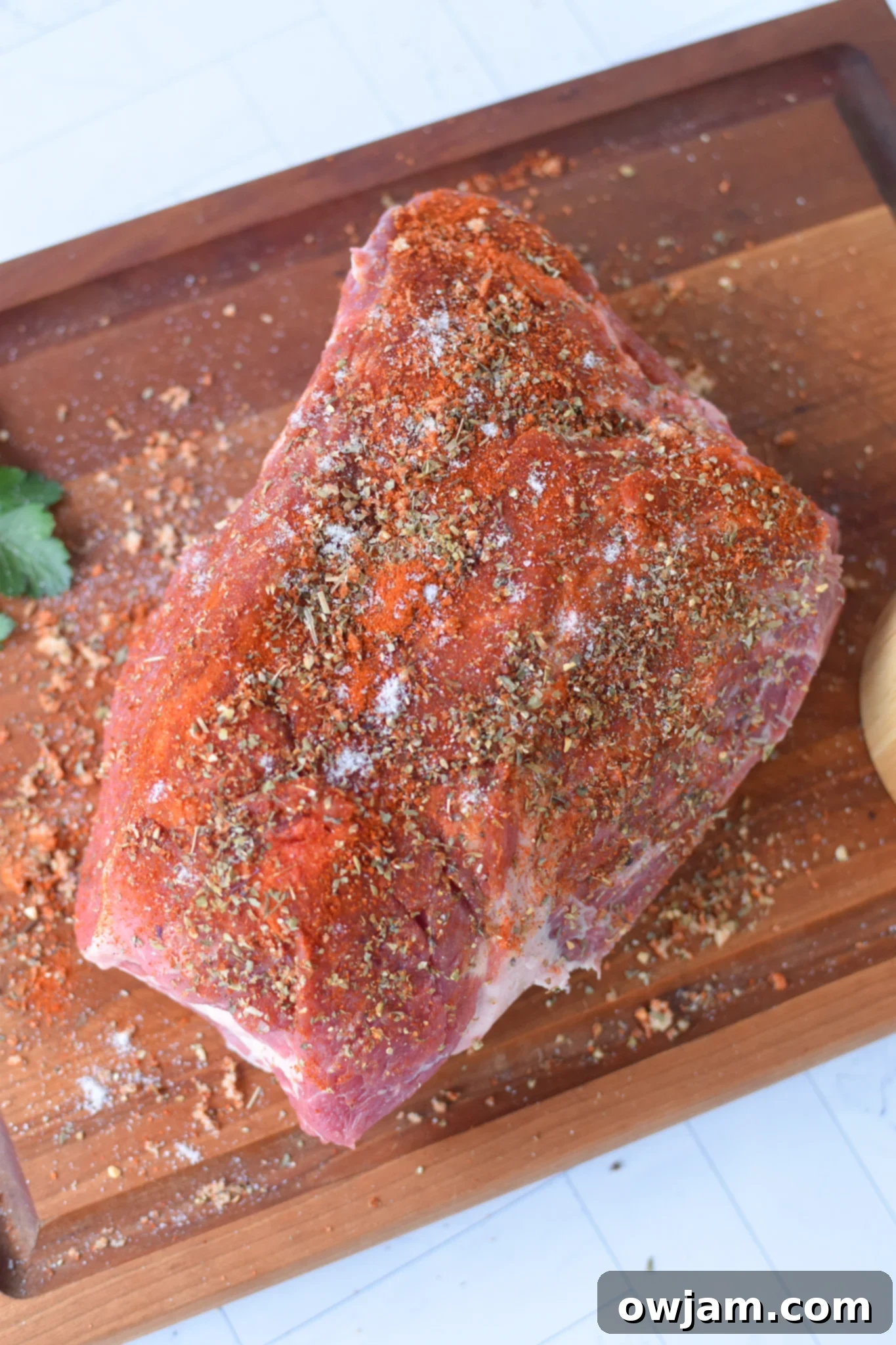 Effortless Oven Pulled Pork Perfection 4 Spice rub being applied generously to a pork Boston butt before it's cooked, ensuring full coverage.